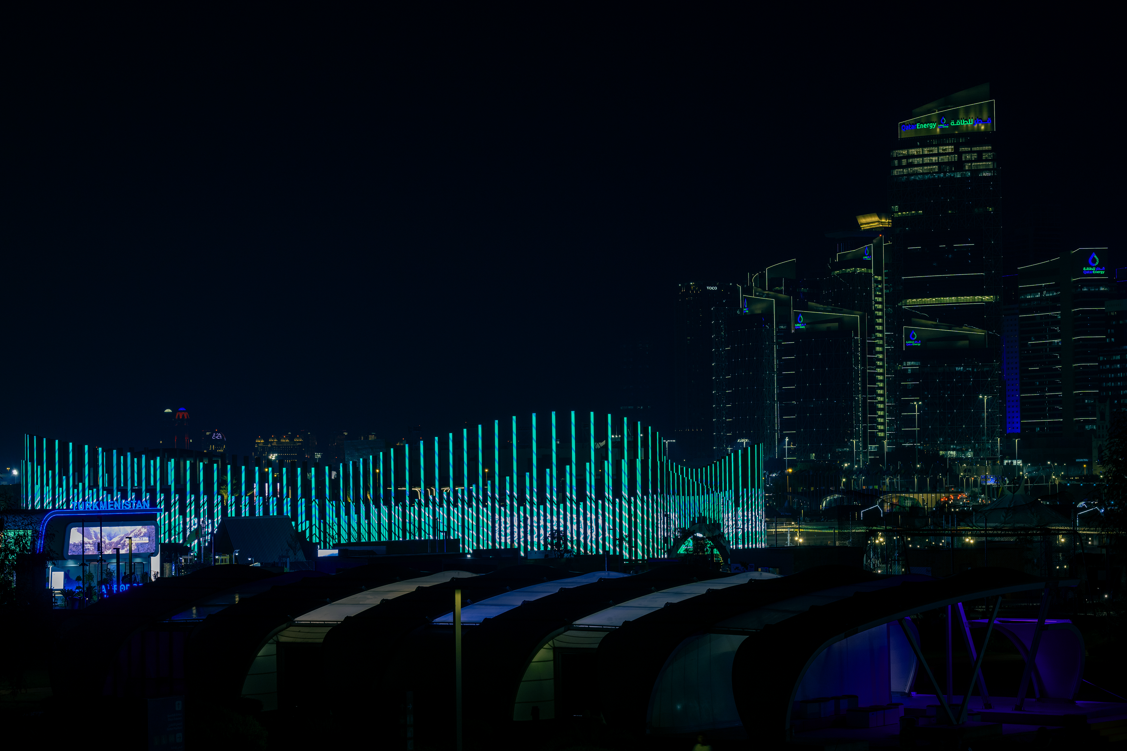Night view of the KSA facade with the skyline of Doha in the background