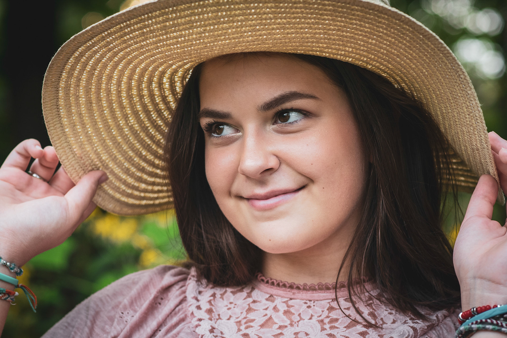 high school senior girl with brown eyes, brown hair, straw hat and pink top