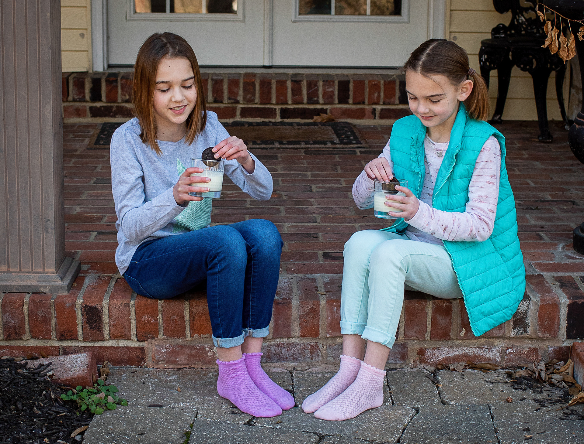 girls dunking cookies into milk on the porch