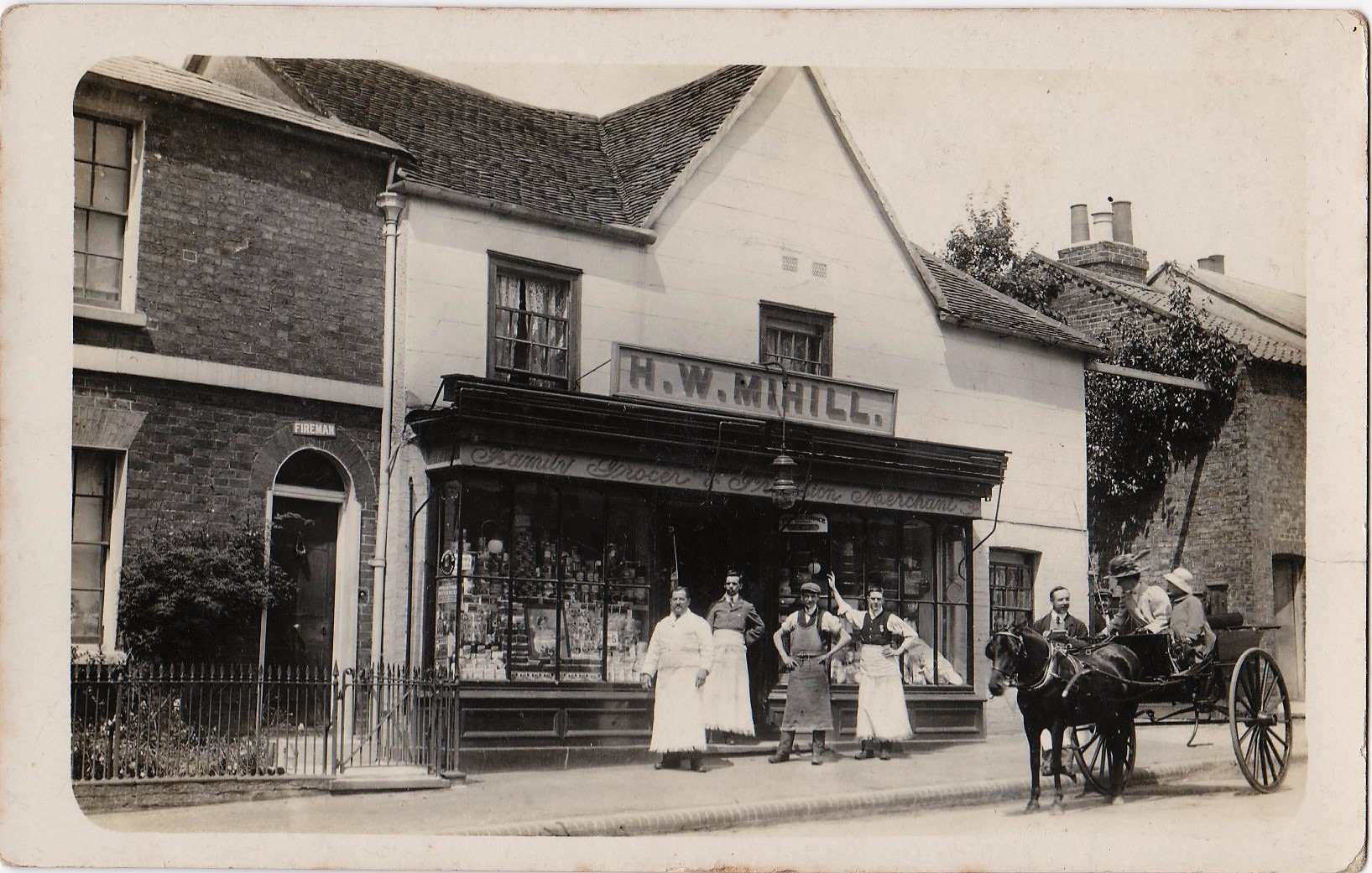Henry William Mihill & staff outside his grocery store circa 1911. The sign on the attached house says 'Fireman', the small gap to the right of the grocers was the fire station yard. The shop is a private residence now.