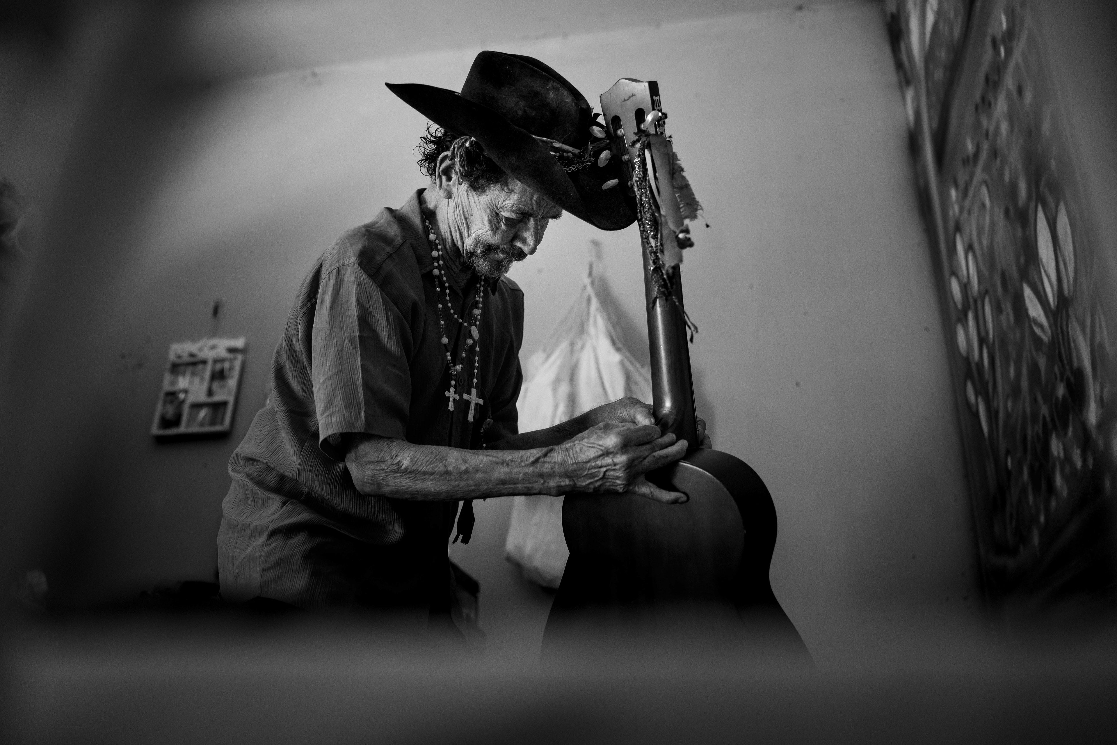 Pipa attaches a strap to a guitar in his room at the Saint Vincent de Paul Home in Cidade de Goiás, Go., Friday, March 6, 2026. Living with an intellectual disability, he often turns to music as a way to spend his time. (© Camden Hall)