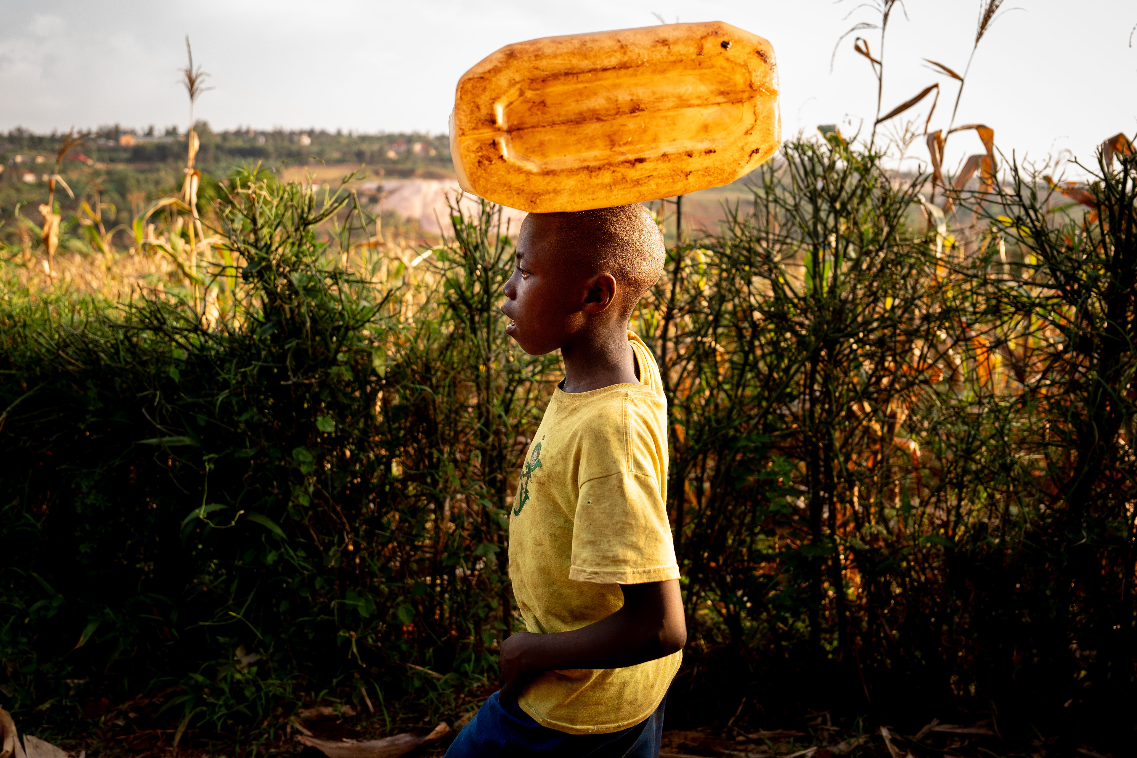 A young boy carries a canister of water on his head from the local well near the Murindi Village in Kigali, Rwanda, Monday, March 3, 2025.