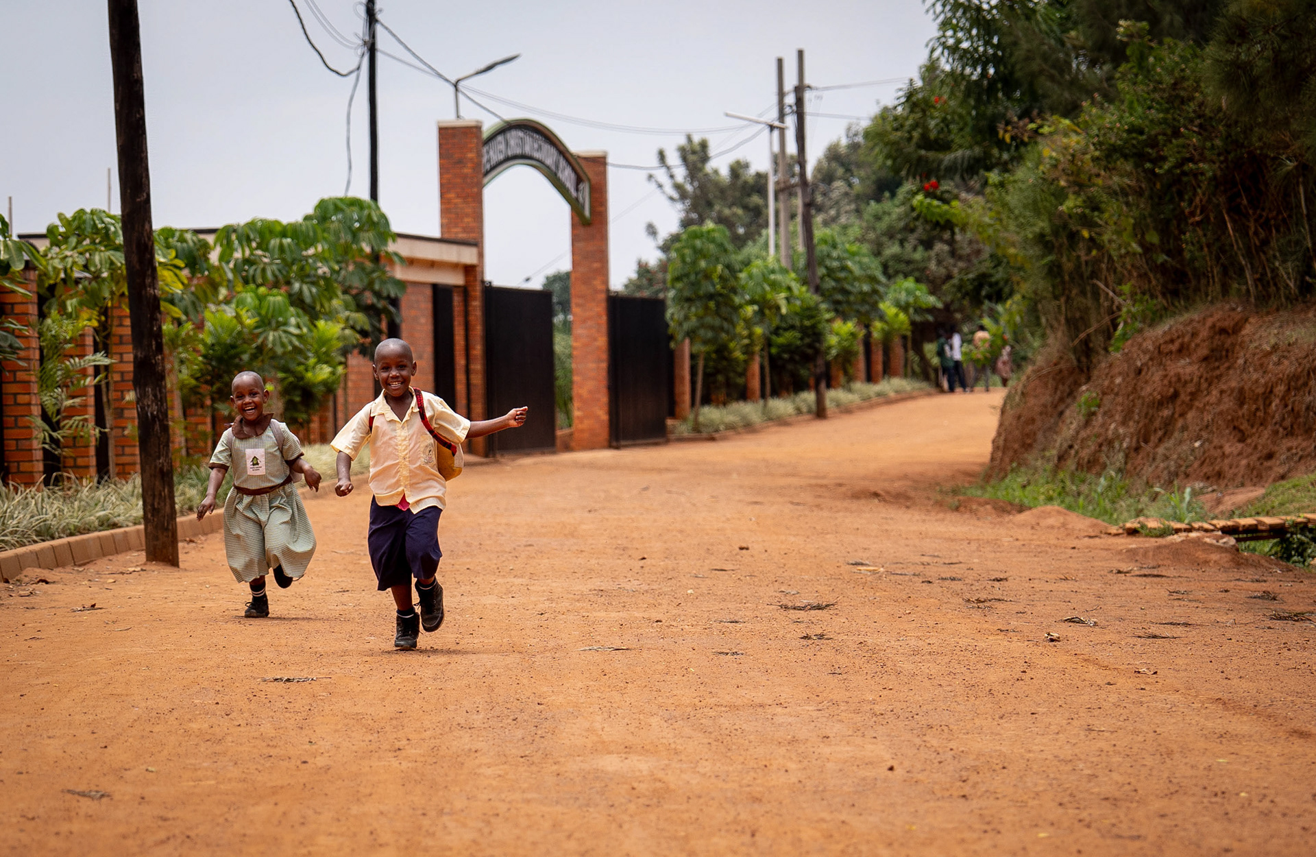 Children play on the road while walking home from school near the Murindi Village in Kigali, Rwanda, Monday, March 3, 2025.
