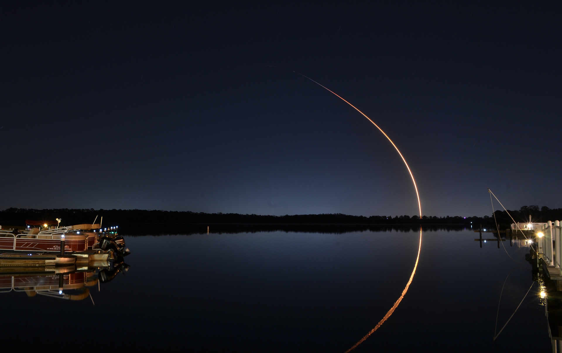 A Falcon 9 rocket arches over a lake after lifting off from the Kennedy Space Center on mission Starlink 21 (L22) in Orlando, FL, Sunday, Mar. 14, 2021. 