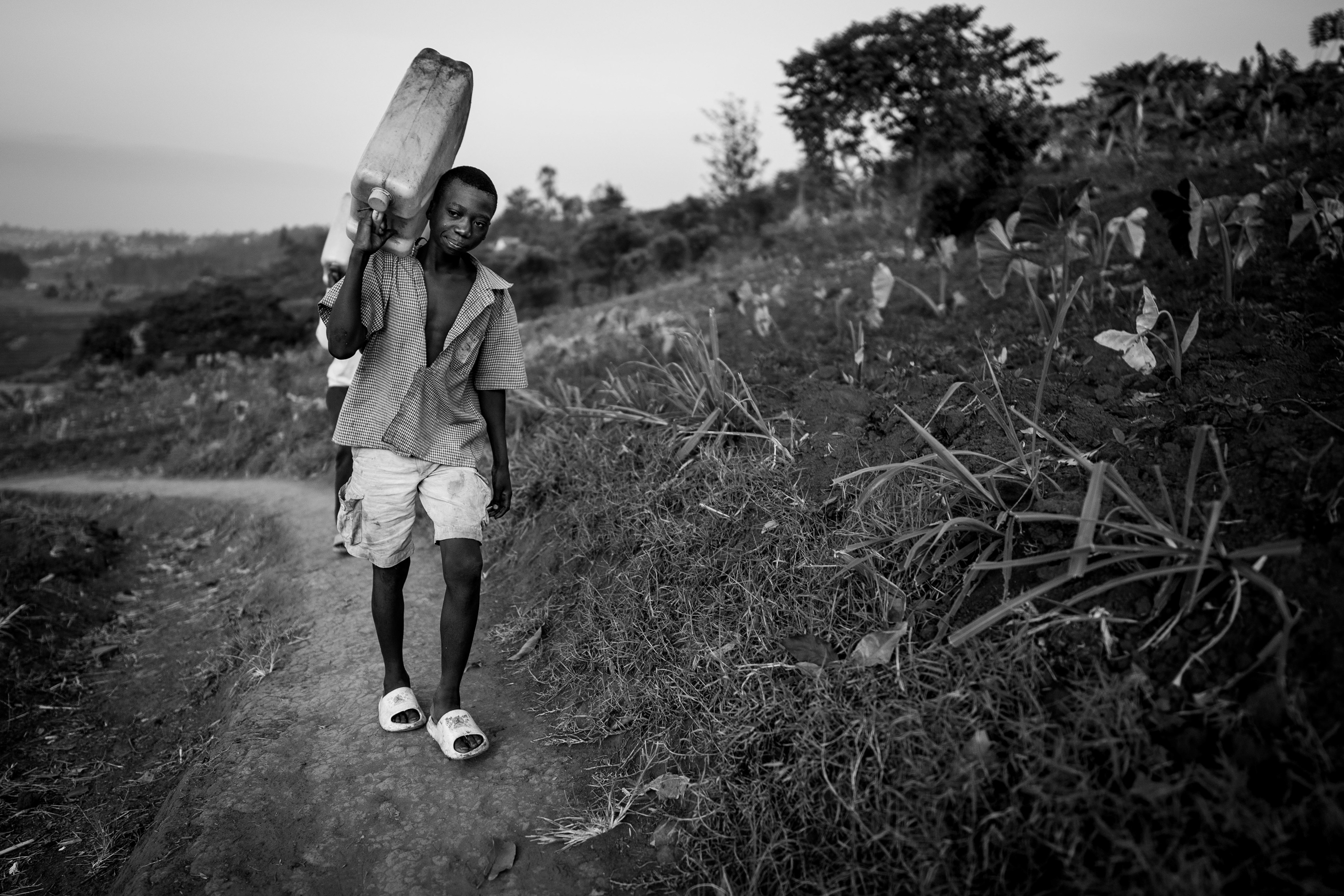 People carry water canisters from the local well near the Murindi Village in Kigali, Rwanda, Thursday, March 6, 2025.