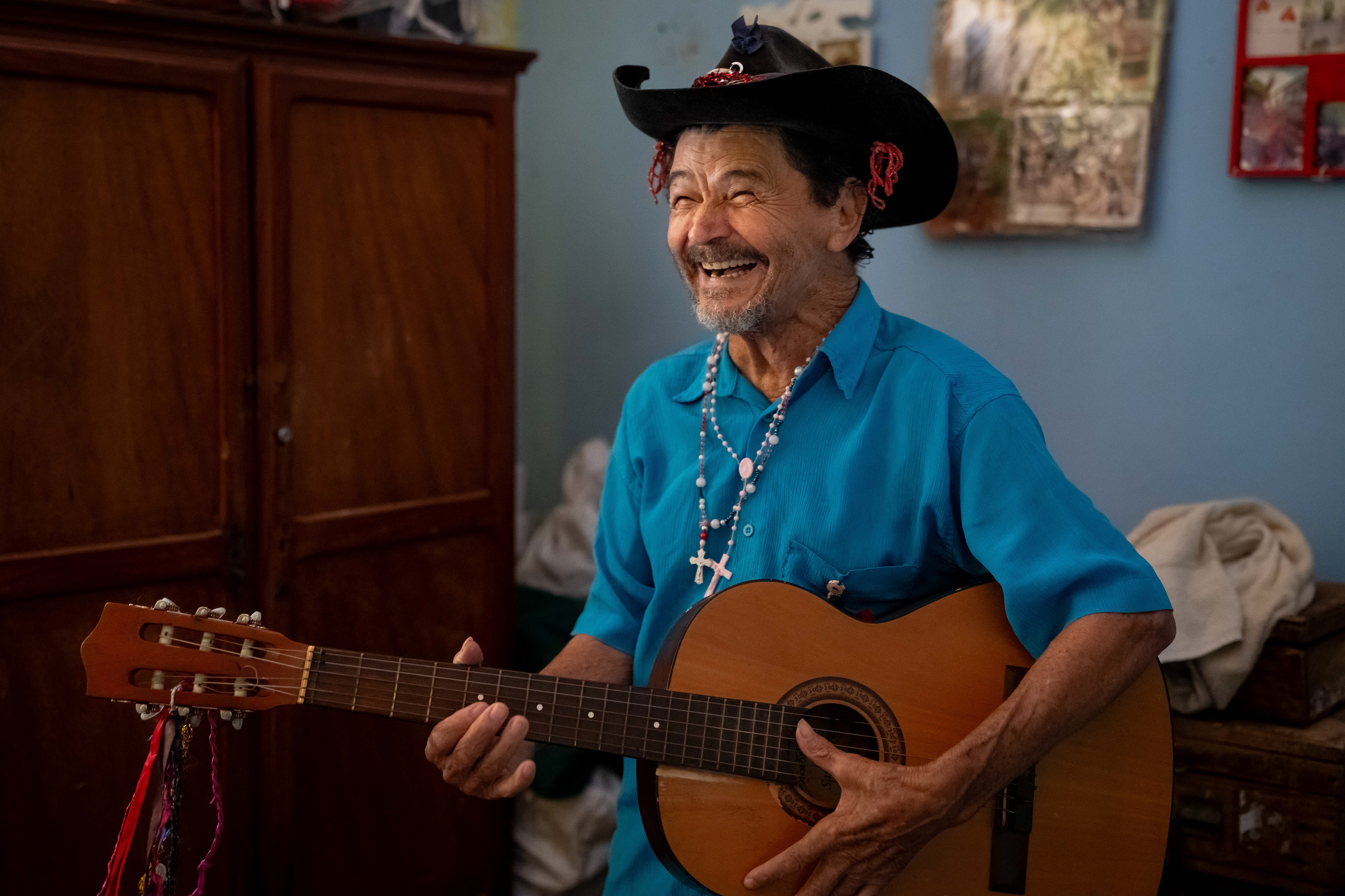Pipa plays his guitar in his room at the Saint Vincent de Paul Home in Cidade de Goiás, Go., Friday, March 6, 2026. Living with an intellectual disability, he often turns to music as a way to spend his time. (© Camden Hall)