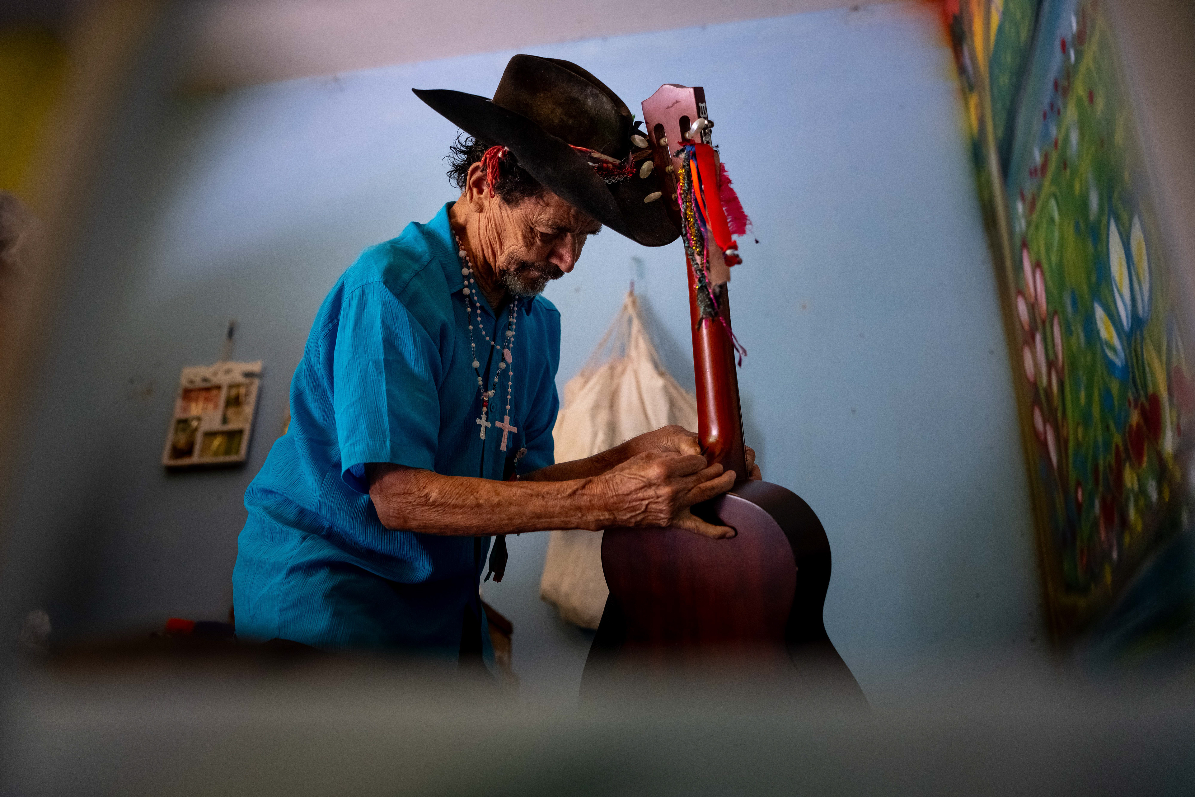 Pipa attaches a strap to a guitar in his room at the Saint Vincent de Paul Home in Cidade de Goiás, Go., Friday, March 6, 2026. Living with an intellectual disability, he often turns to music as a way to spend his time. (© Camden Hall)