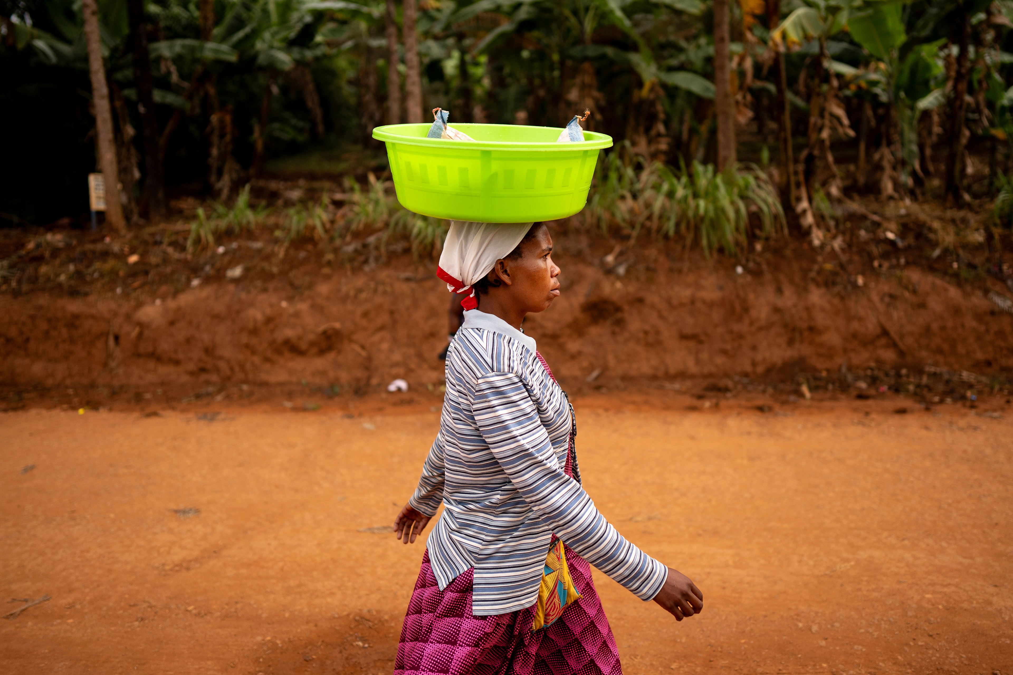 A women carries a bucket on her head near the Murindi Villiage in Kigali, Rwanda, Monday, March 3, 2025.