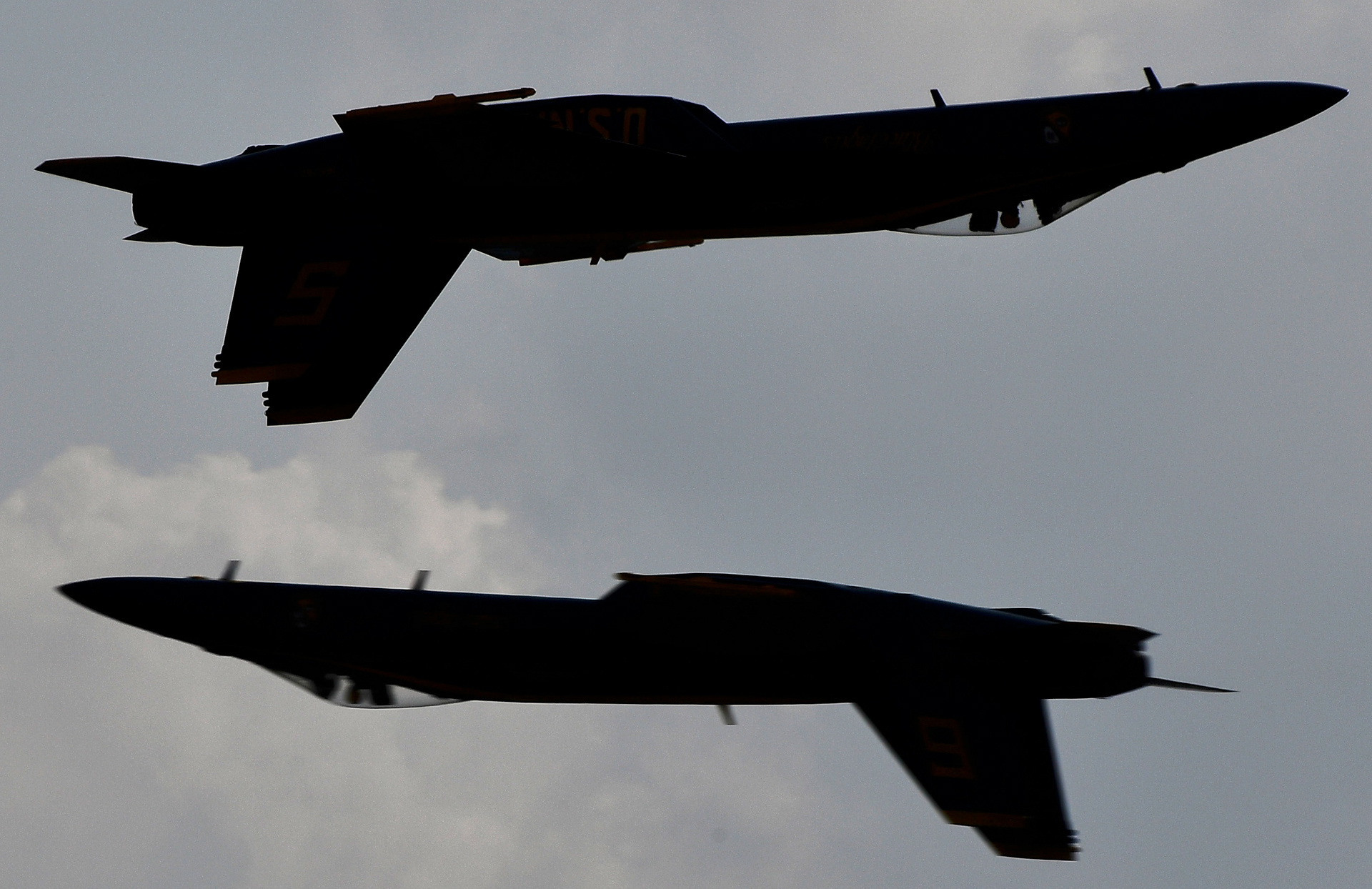 Two Blue Angles jets are silhouetted while flying inverted as they pass each other in Smyrna, Tenn., Saturday, June 10, 2023.