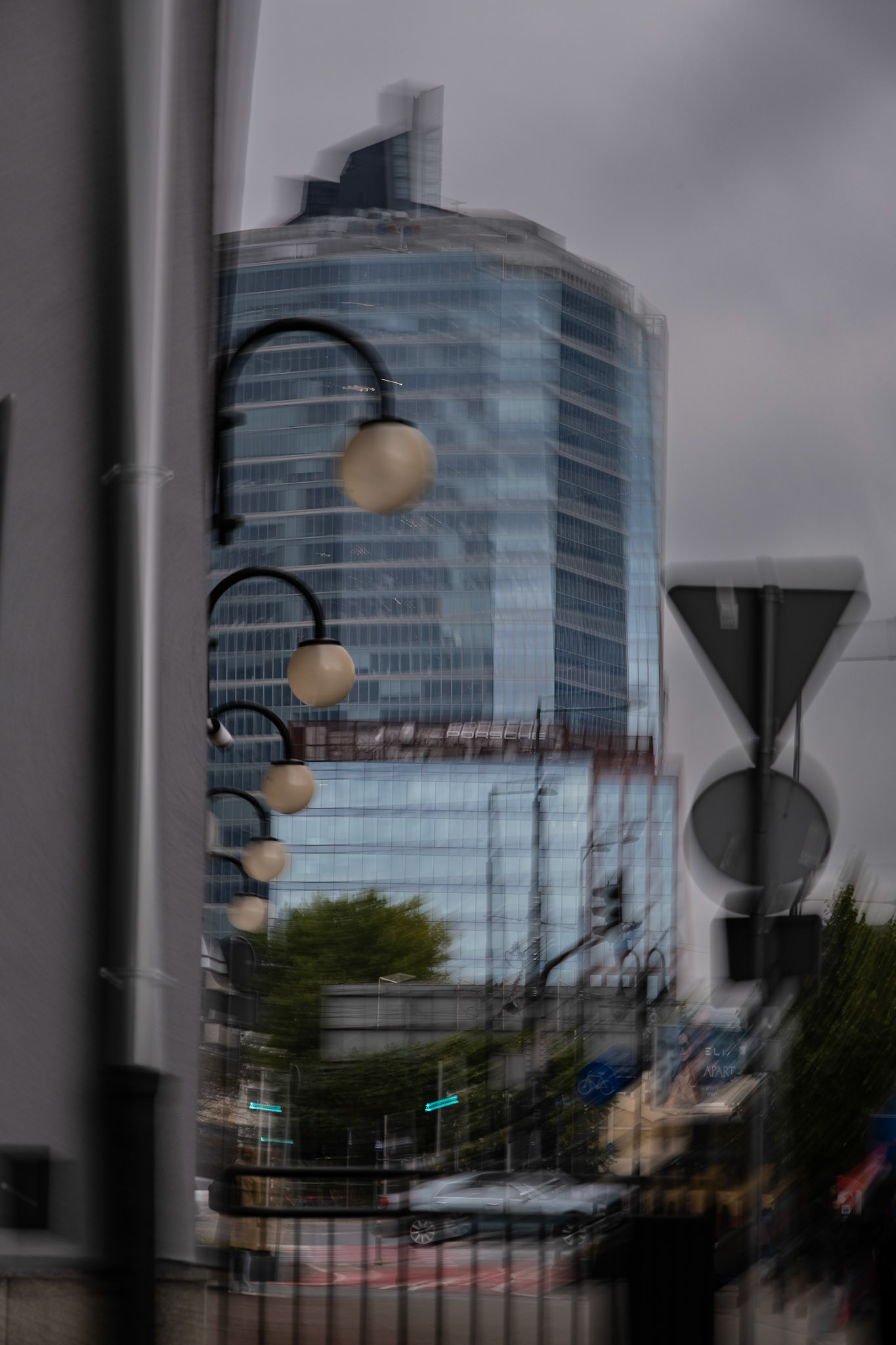 Photography of a street view of a glass skyscraper reflecting clearing sky with clouds in the background