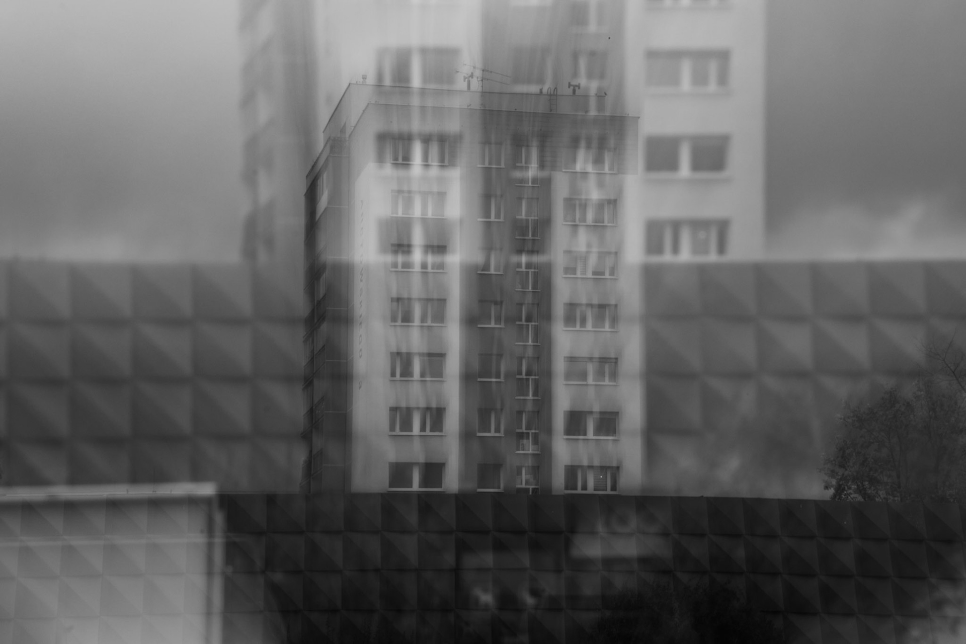 Abstract black and white cityscape featuring a tall residential building with blurred vertical motion effects, showcasing ICM photography techniques to create a dreamy, surreal atmosphere.