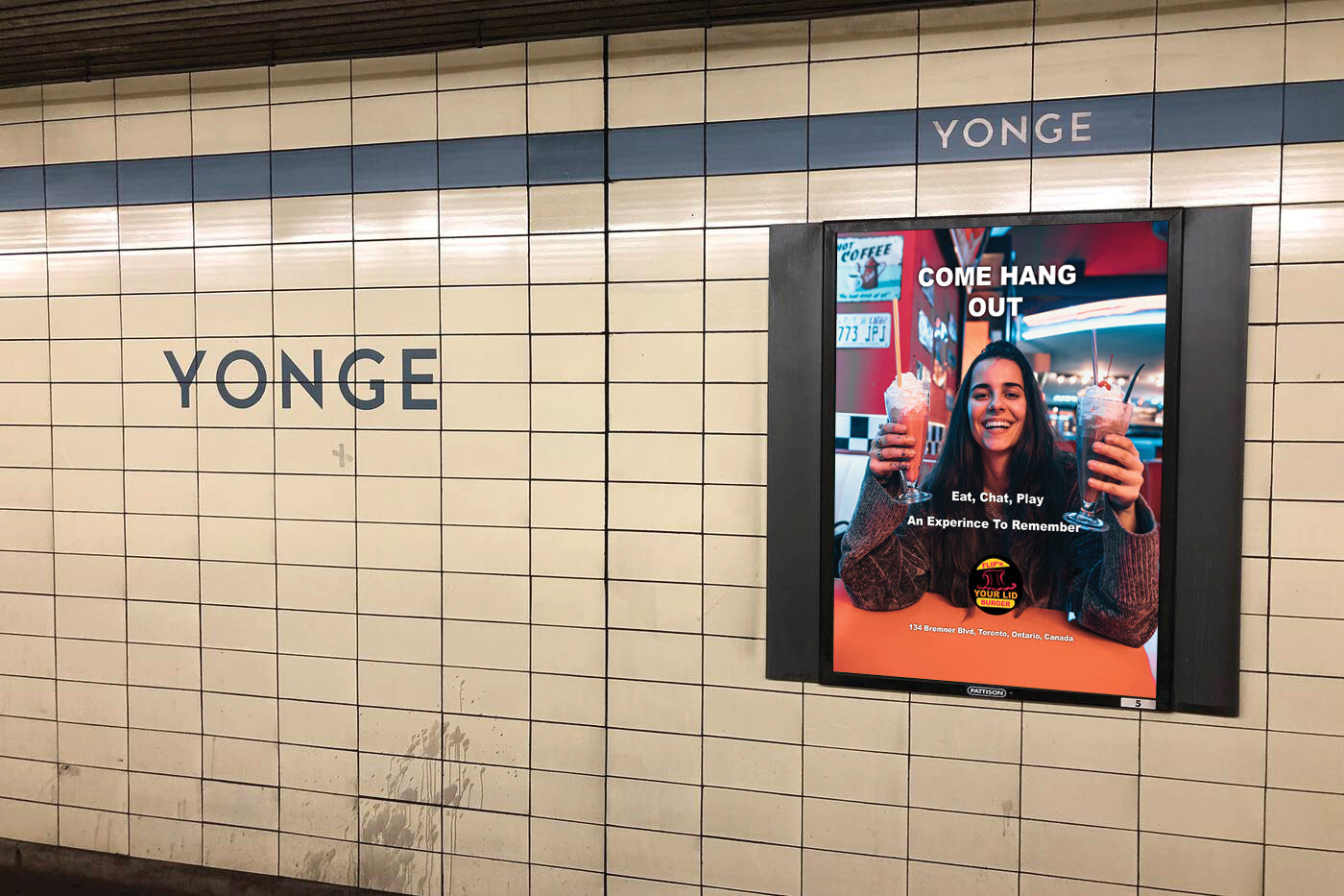 In this image is an advertisement that will be placed in the subway at Yonge Street where in the advertisement is a female that is smiling sitting down at the Flip'N Your Lid Burger retro diner holding two milkshake drinks where one of them is being held on the left hand and the other is being held on the right hand. The words Come Hang Out, Eat, Chat, Play, An Experience To Remember and the location of the restaurant all in a white colour. The Flip'N Your Lid Burger logo is located at the bottom of the advertisement, but above the restaurant's street location in the ad.