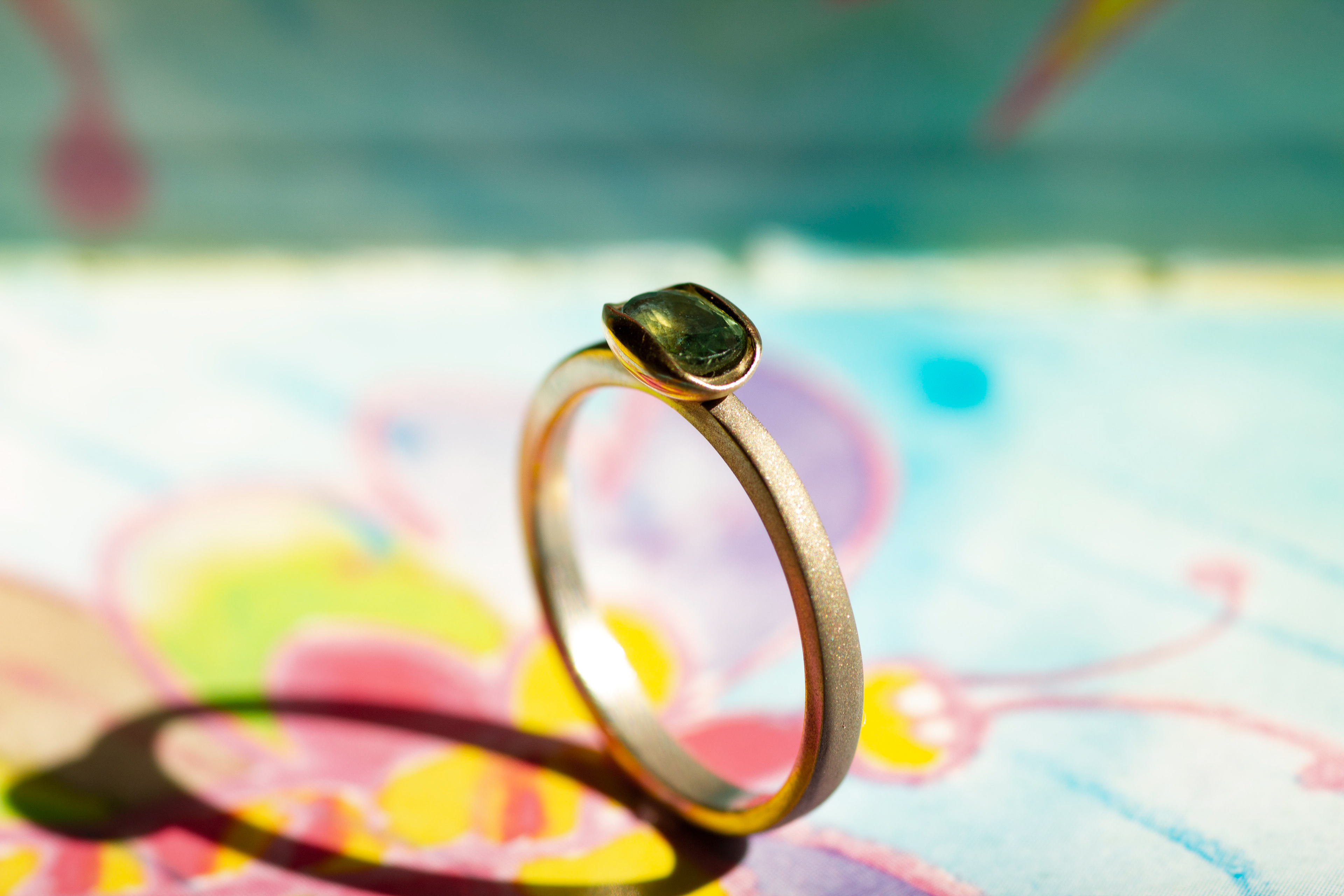 White gold ring with a natural green sapphire, mounted in a yellow gold "soap" setting. Polished, sandblasted.