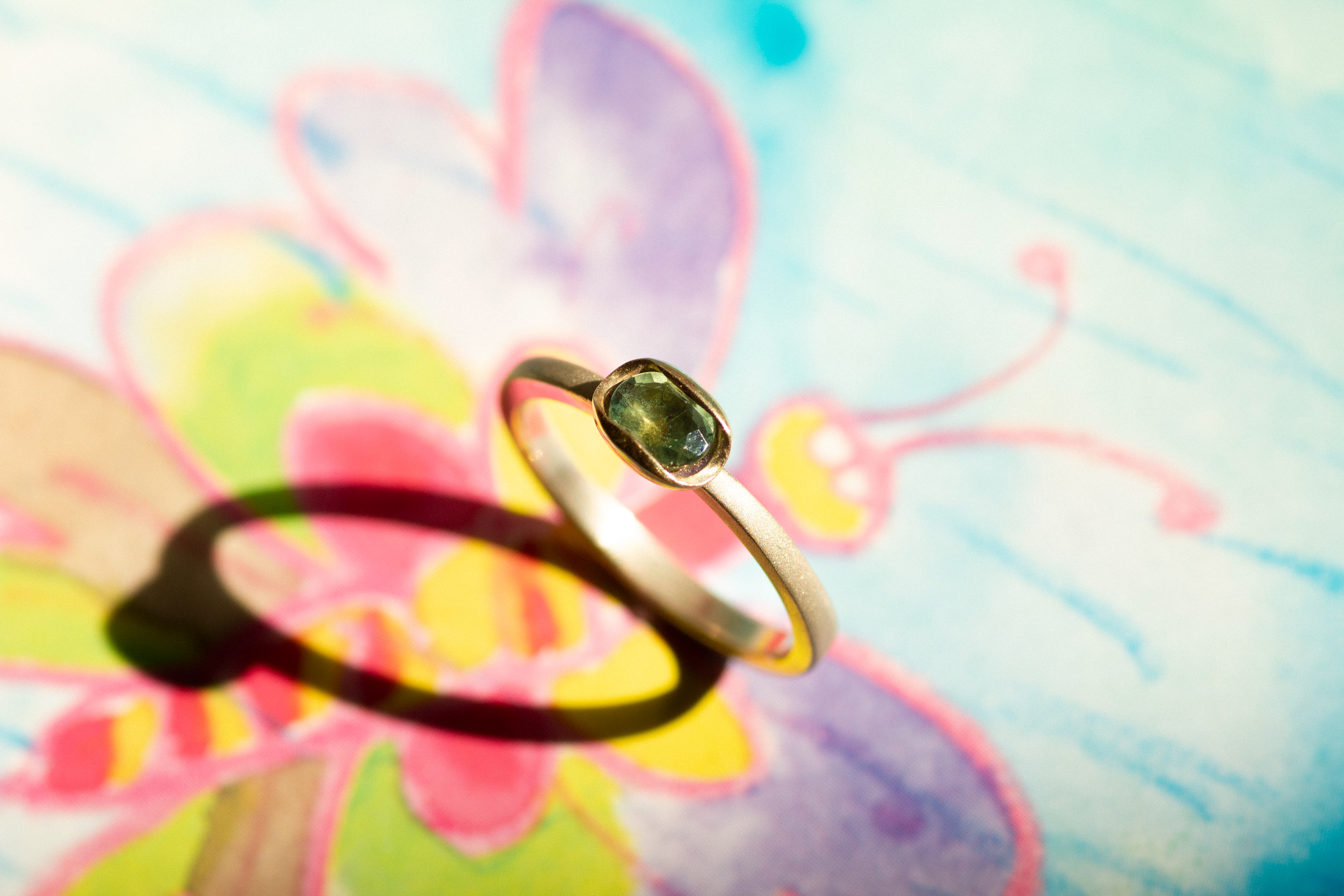 White gold ring with a natural green sapphire, mounted in a yellow gold "soap" setting. Polished, sandblasted.
