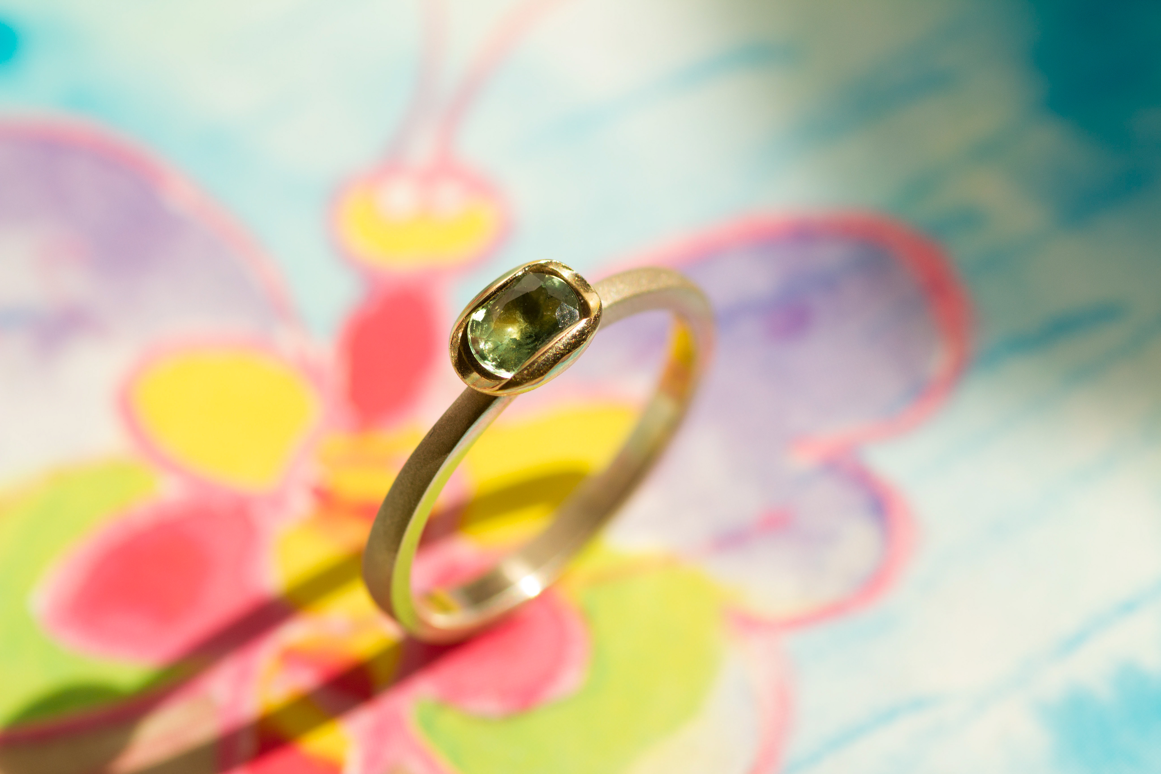 White gold ring with a natural green sapphire, mounted in a yellow gold "soap" setting. Polished, sandblasted.