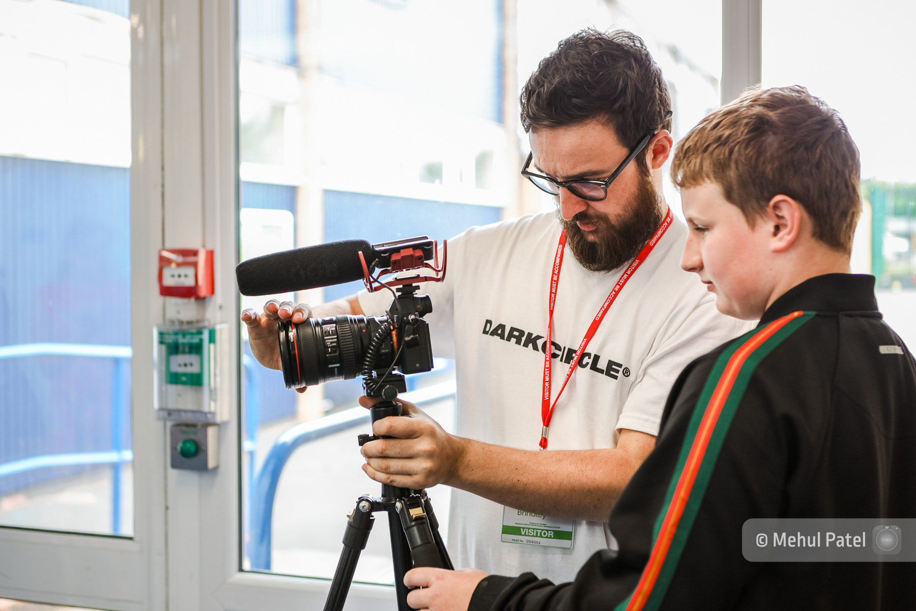 Mentor showing child at school how to operate DSLR camera. Published in client annual report