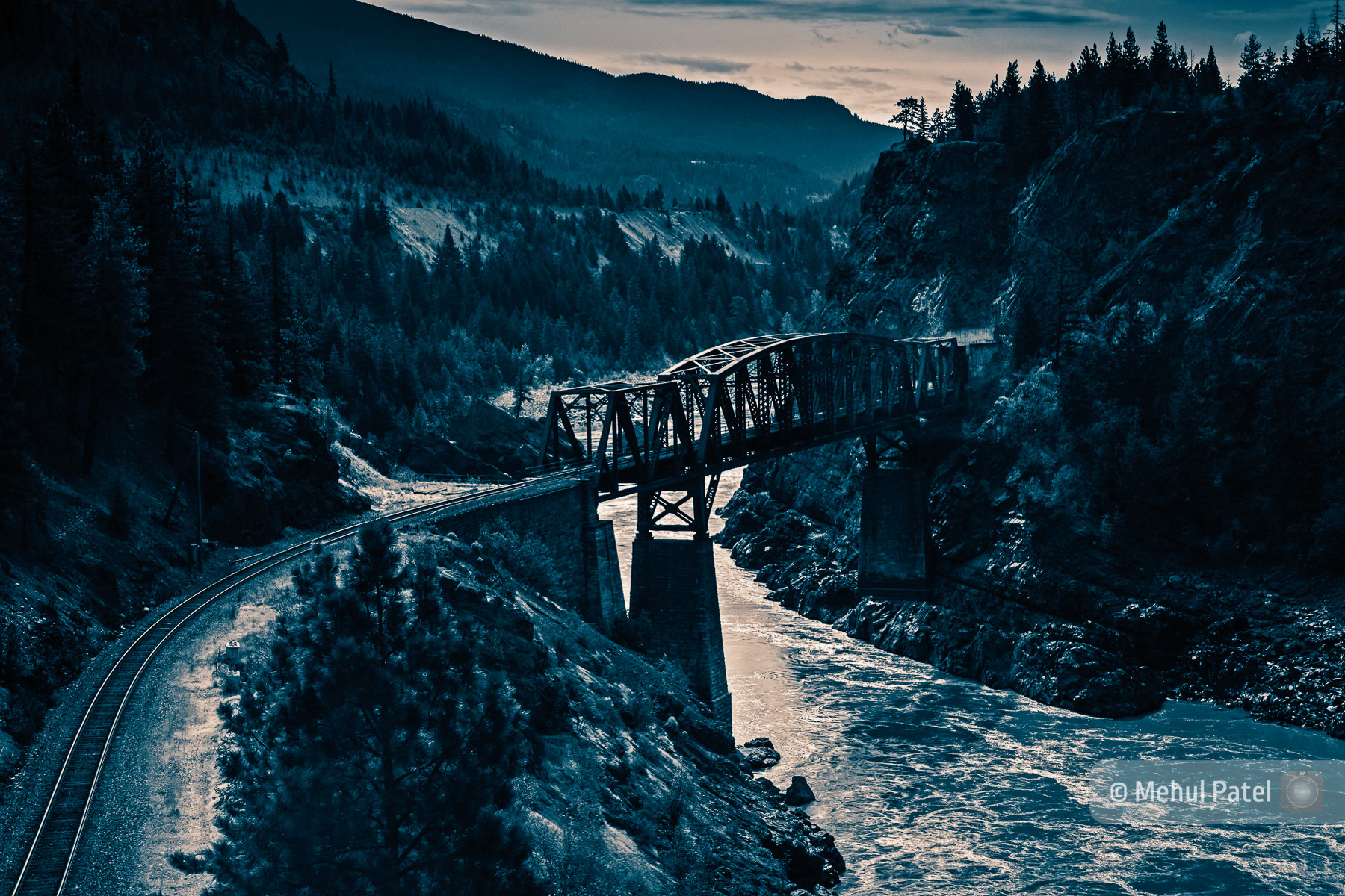 Split tone photo of railway bridge over water in mountains. Published as a book cover.
