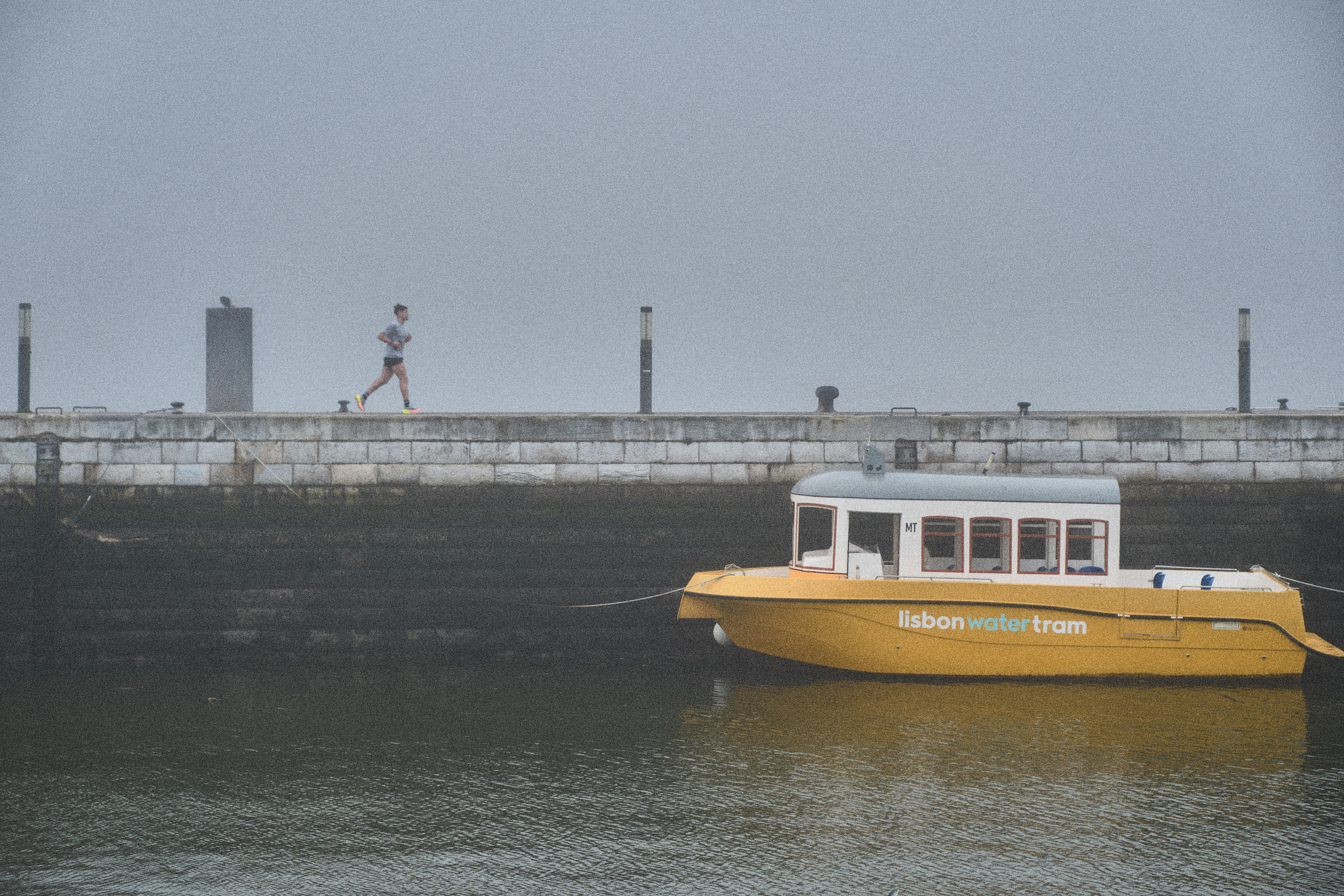 a small yellow boat and a runner on a foggy morning