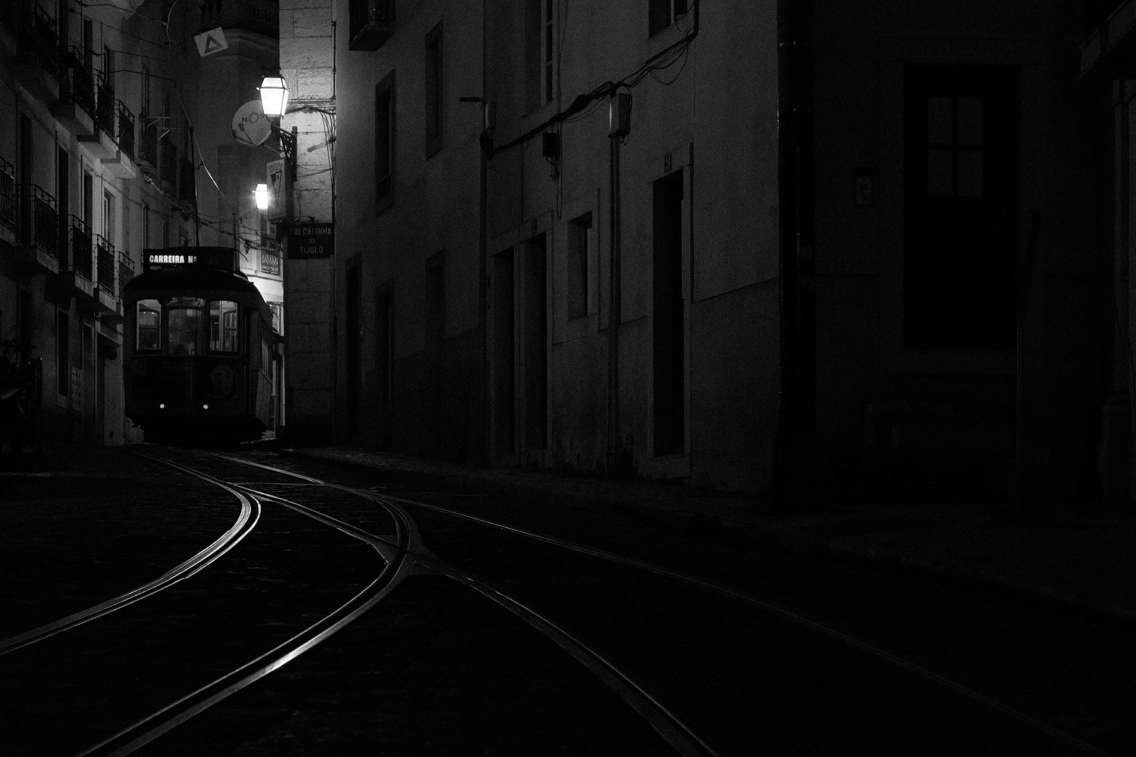 a classic night scene in the streets of Lisbon: the tram through the narrow streets under the light of lampposts