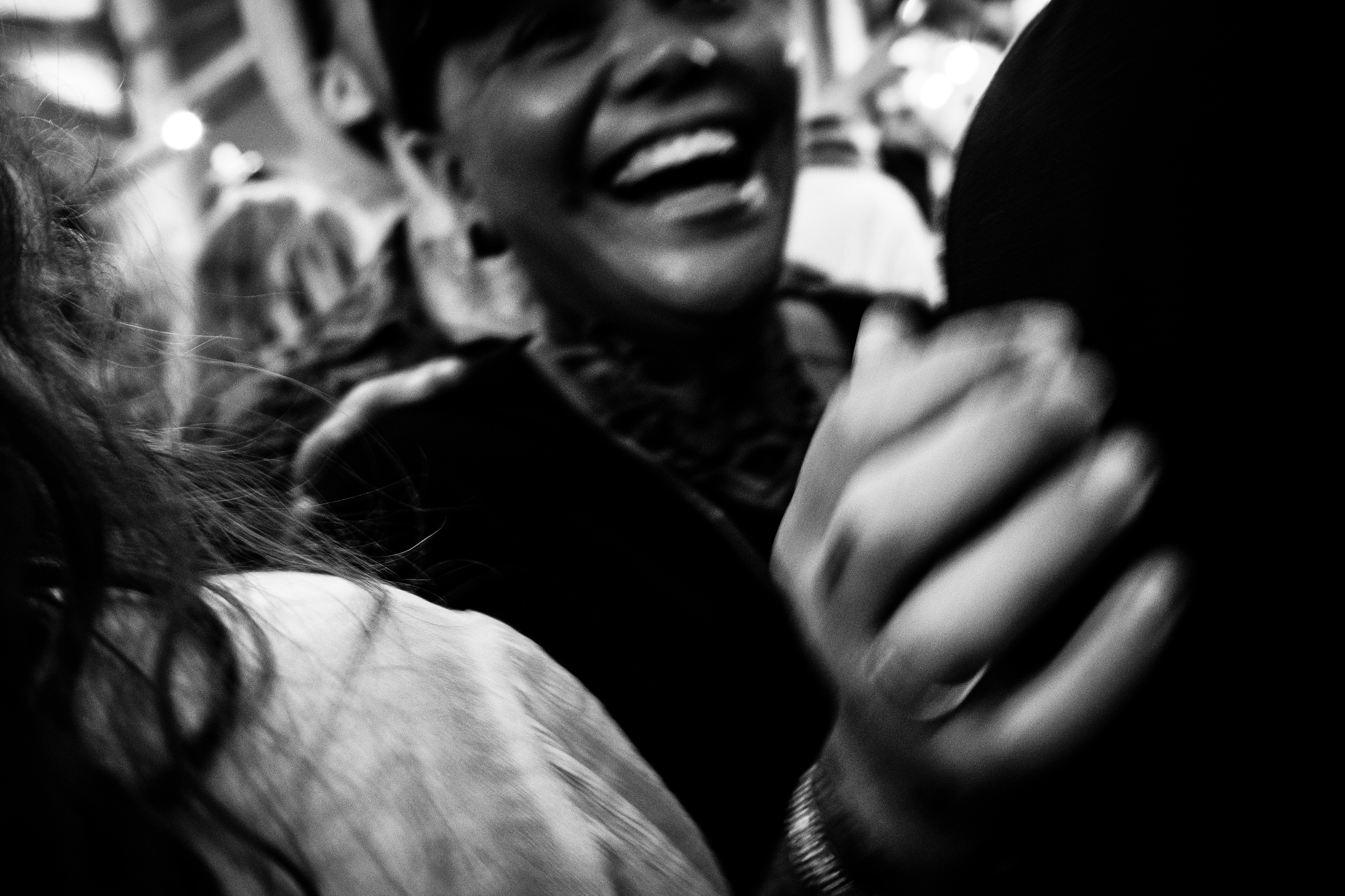 A black and white image of a woman smiling and enjoyind the crowd in a street party during Santos in Lisbon