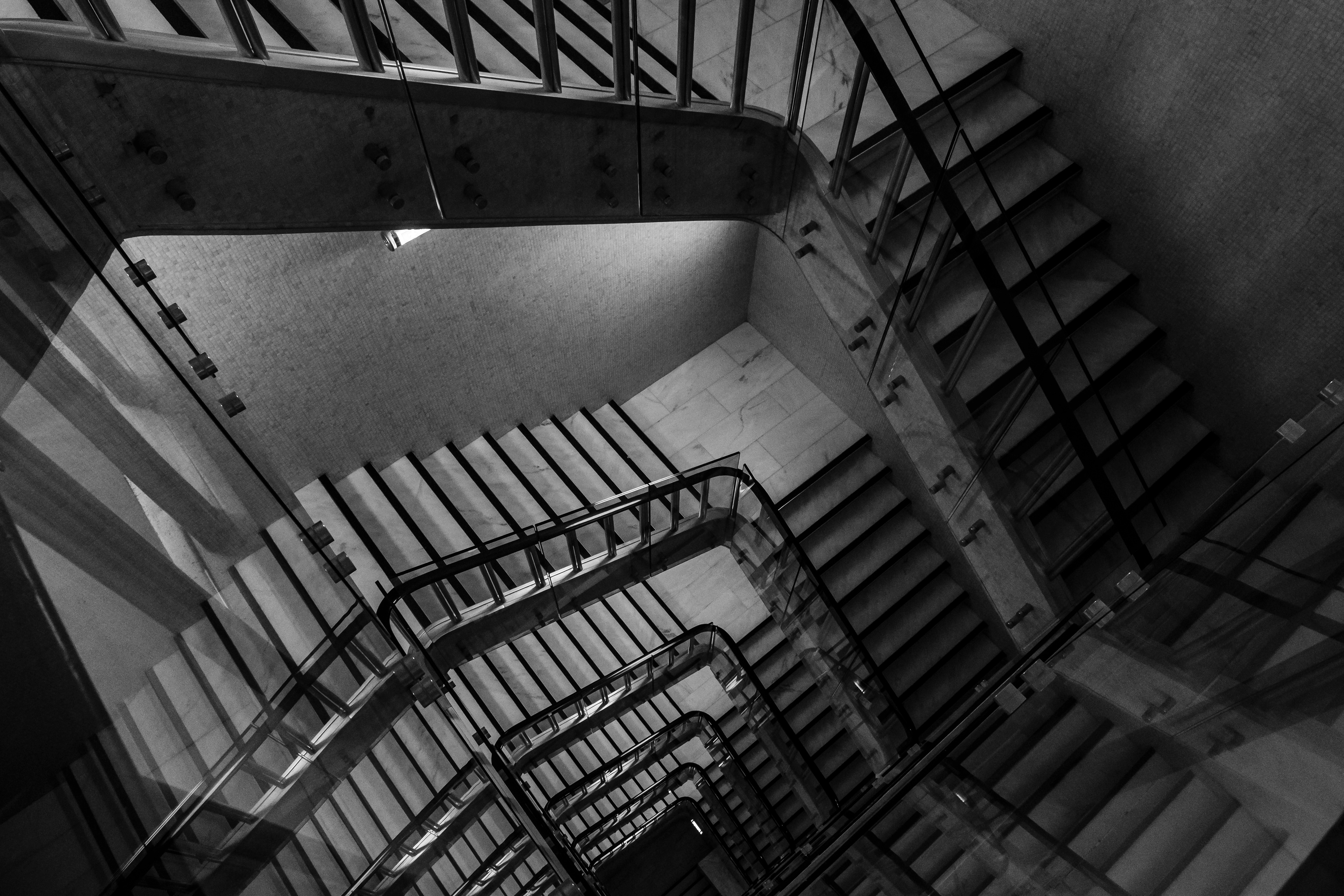Black and white view of staircase that reflects in windows with a hint of Escher