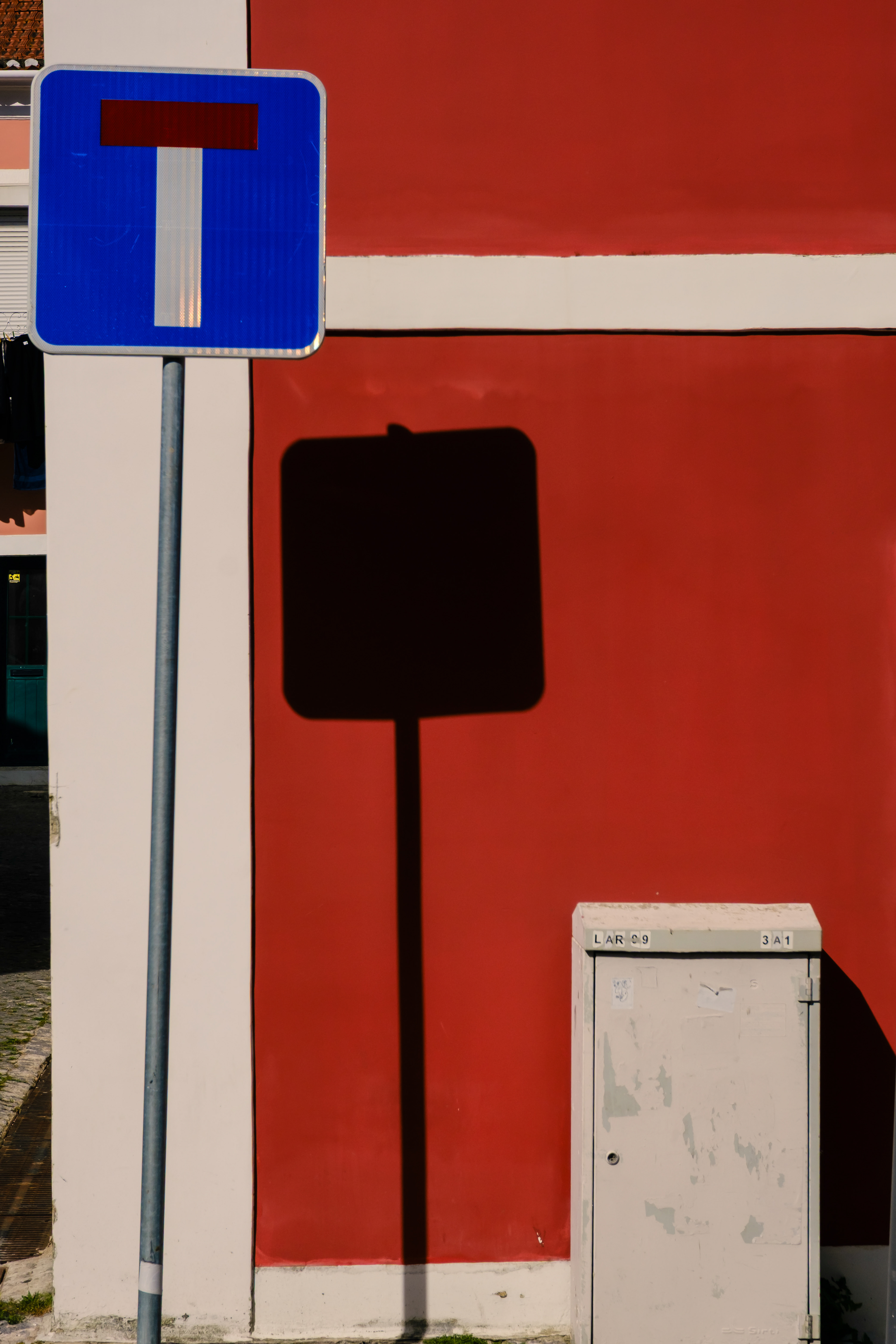 a blue traffic sign in front of a red wall