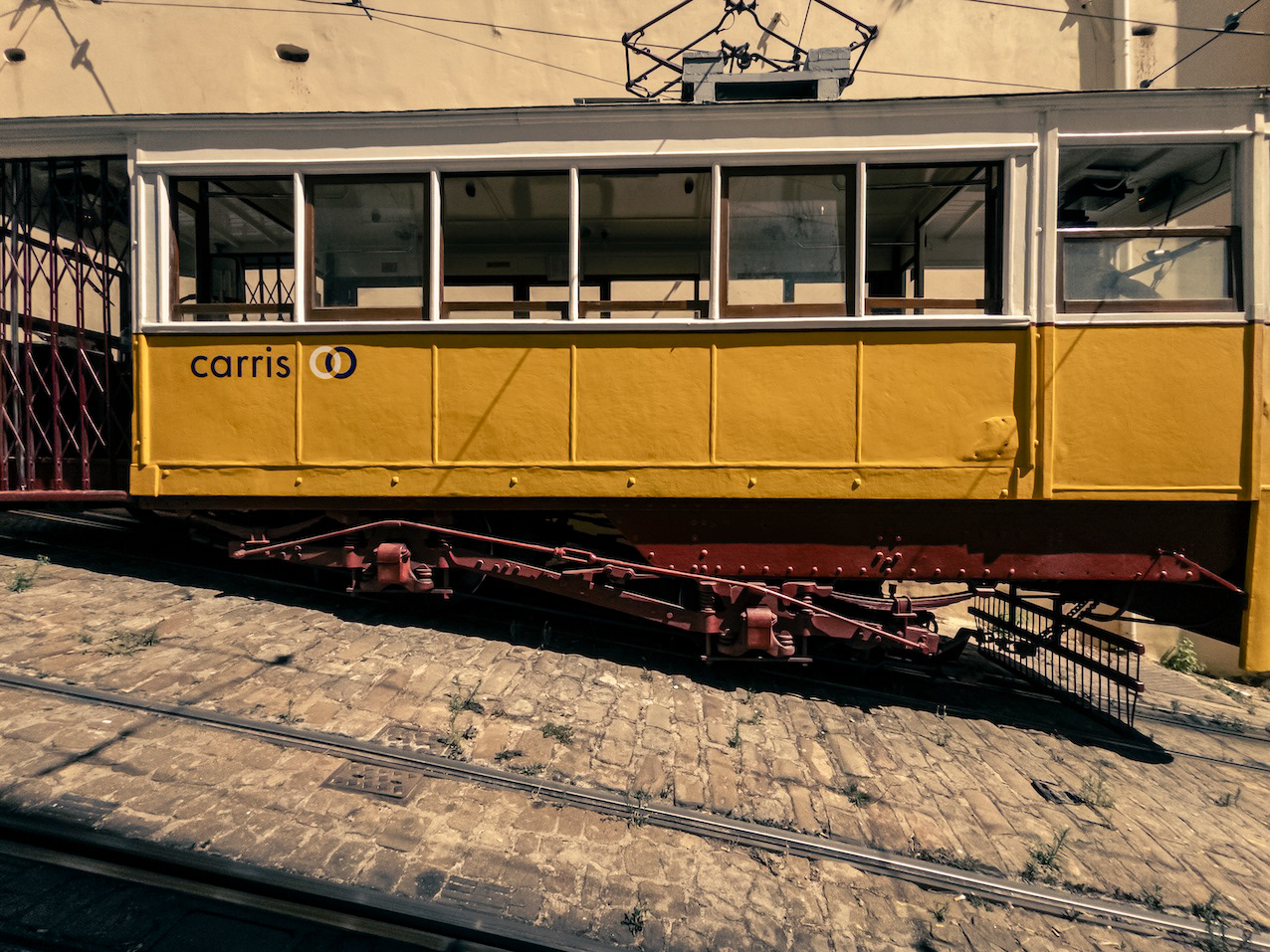 A yellow tram-elevador (funicular) is seen against a yellow wall in central Lisbon