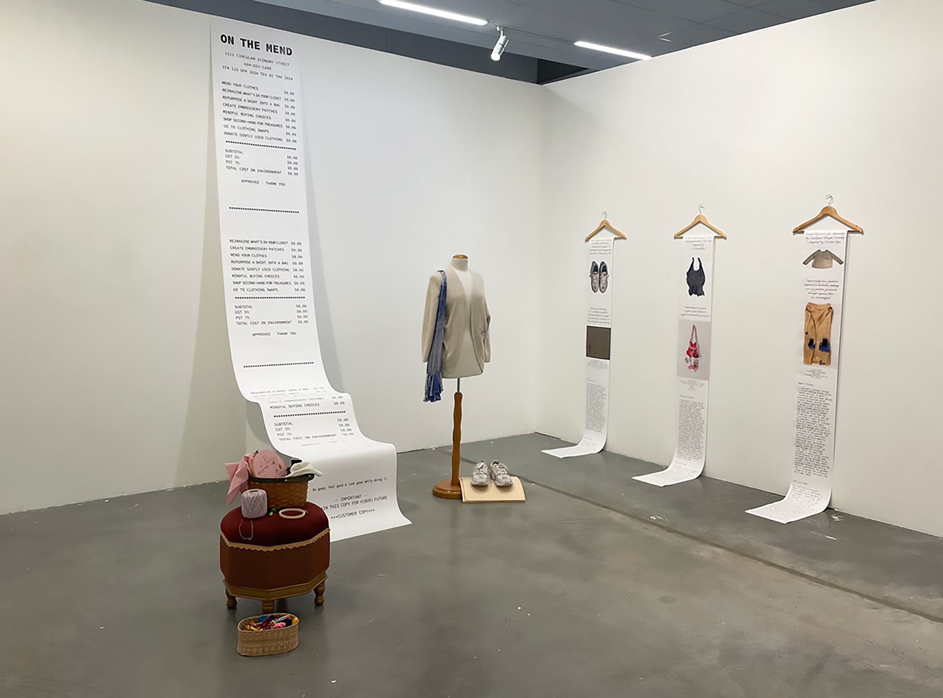 Natalie R. Chiovitti, On the Mend, 2024 Gallery installation design including a large-scale receipt, banners on clothing hangers, seamstress mannequin, cardigan, tote bag, sneakers, ottoman, sewing materials and tools, online Padlet conversation board, & pamphlet, approx. 9 x 19 ft., Elbow Gallery at ECU. 