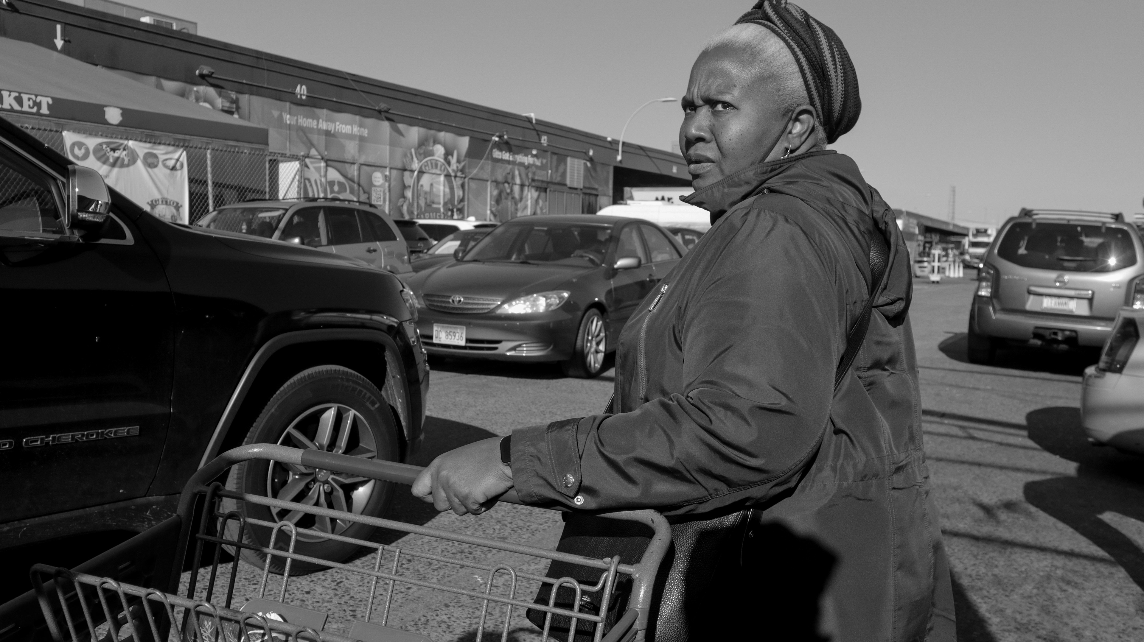 Myrtho waits outside a farmer's market for her son, Alain Pascal, and Jean. She hopes to find two large bags of jasmine rice and black beans to put inside the barrel being shipped to Haiti.