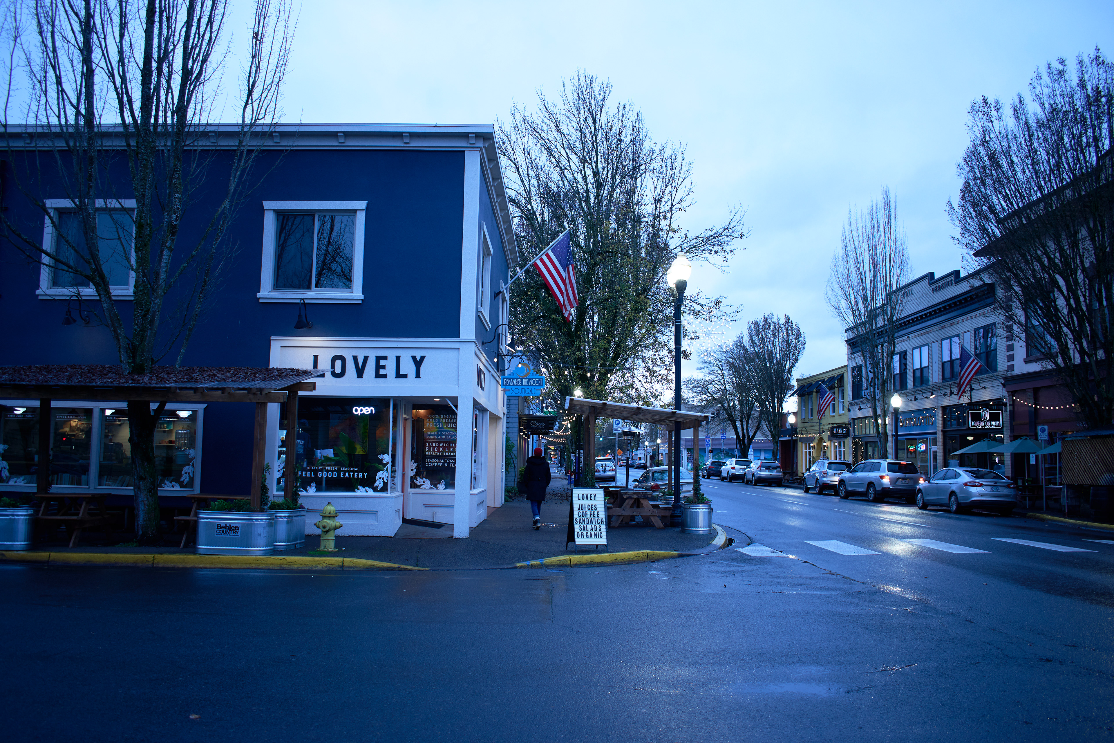 Woman in a red beanie walking down a sidewalk in a downtown area.