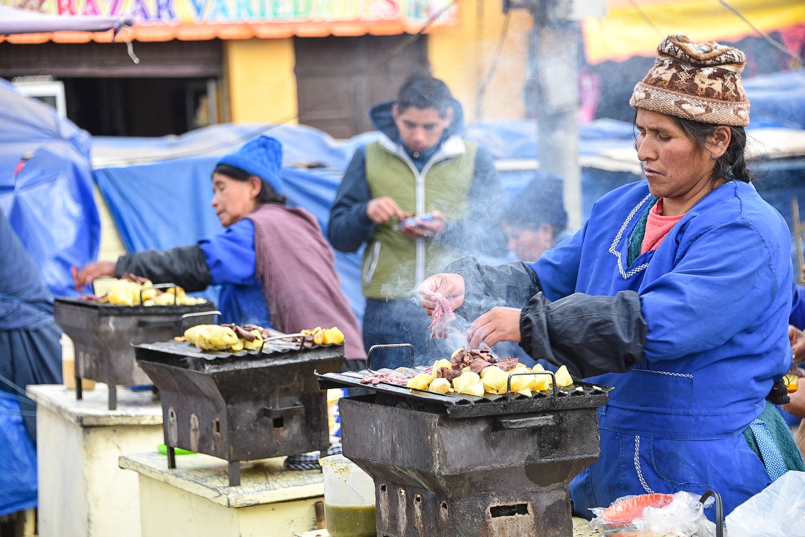 A lady cooks meat and potatoes on a street food stall outside the Mercado Central, Potosi, Bolivia