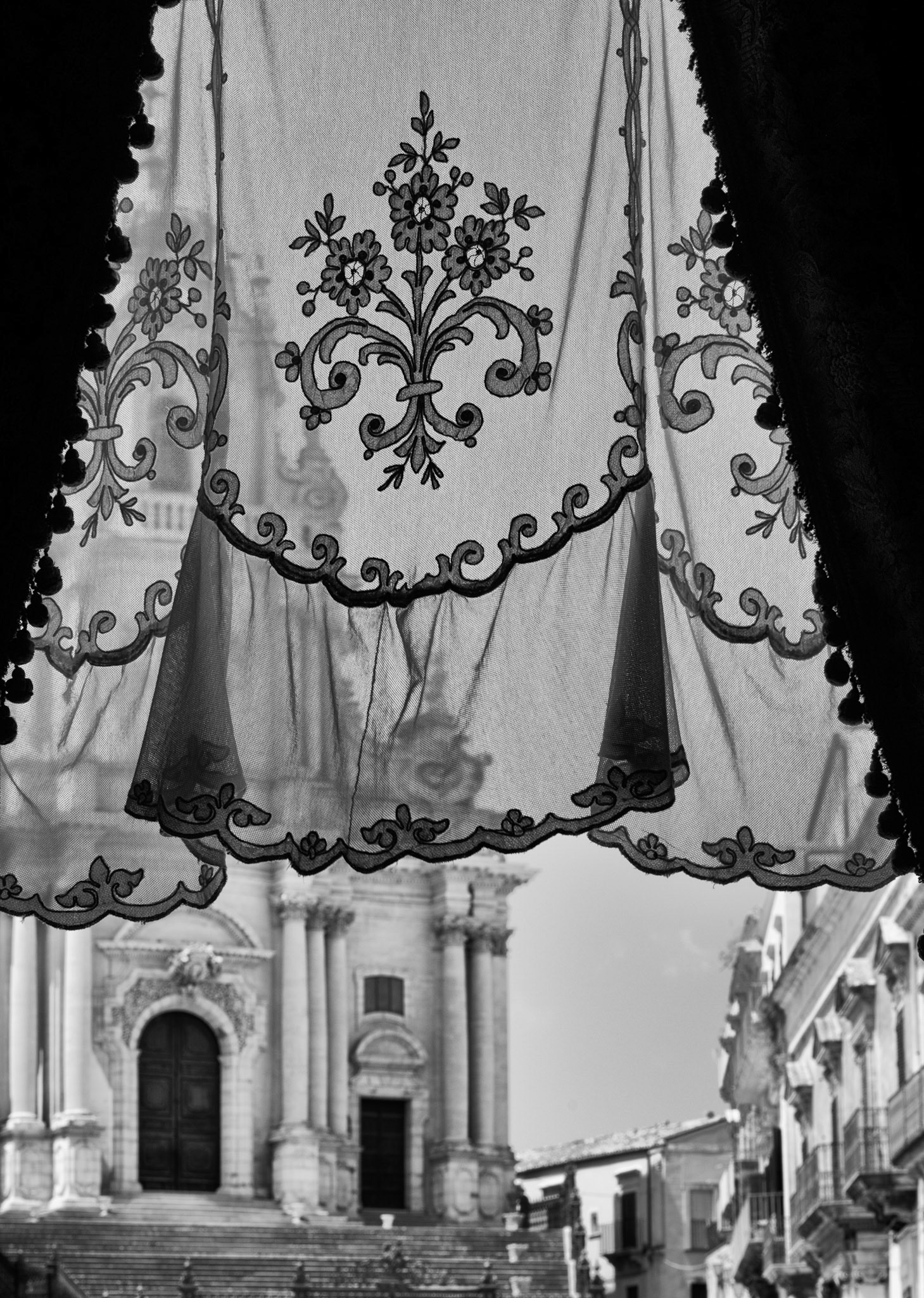This handmade curtain is typically Sicilian. In the background the cathedral of Ragusa Ibla, a beautiful town in the hinterland of southern Sicily.