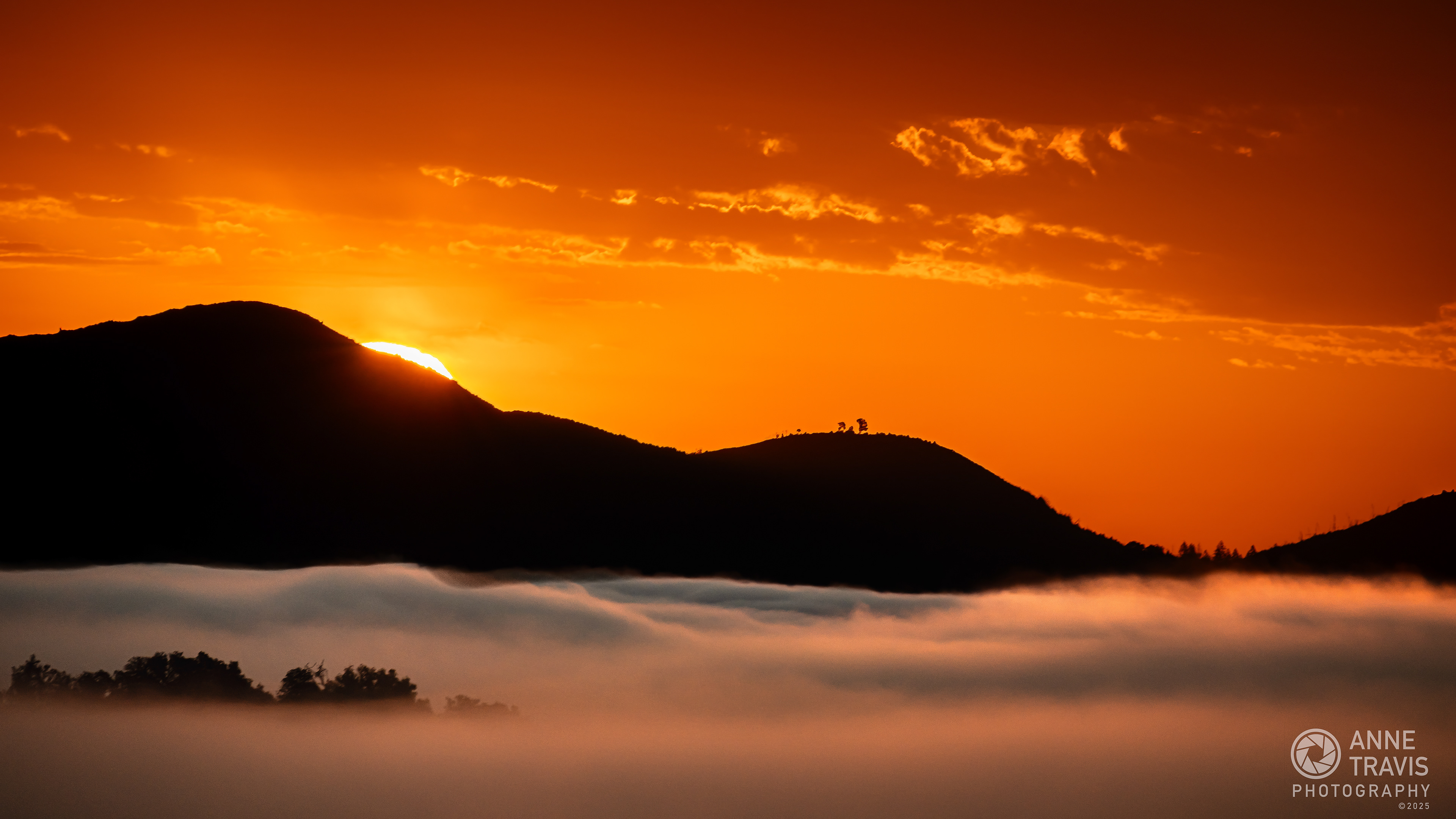 Photo  taken as the sun rose over the Mayacamas Mountains that separate Sonoma and Napa, California. Below the peaks of the mountain range, the morning inversion layer blankets Sonoma in clouds.