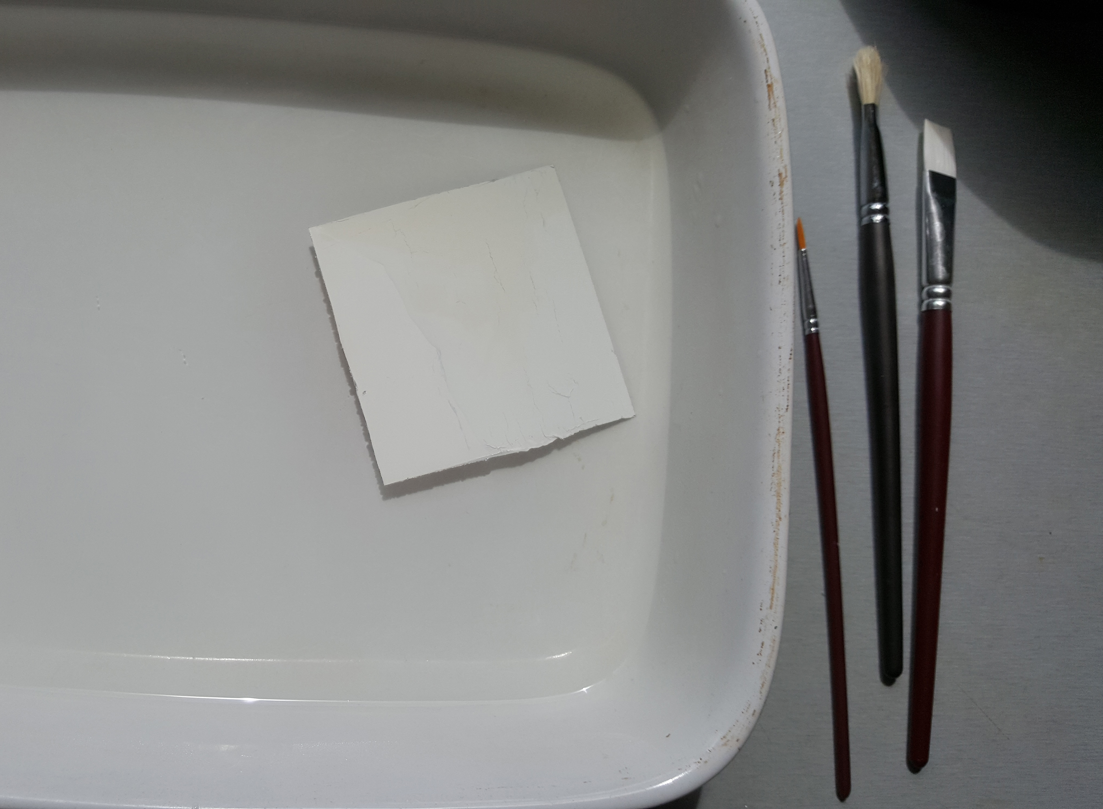  Pour the boiling water into the dish to the depth of about one inch. Remember this is boiling water so watch your fingers!  Put the film into the water face down, if the film is newly developed the white developing chemical should have been left behind on the back of the film, if not this is the time to try and remove it.