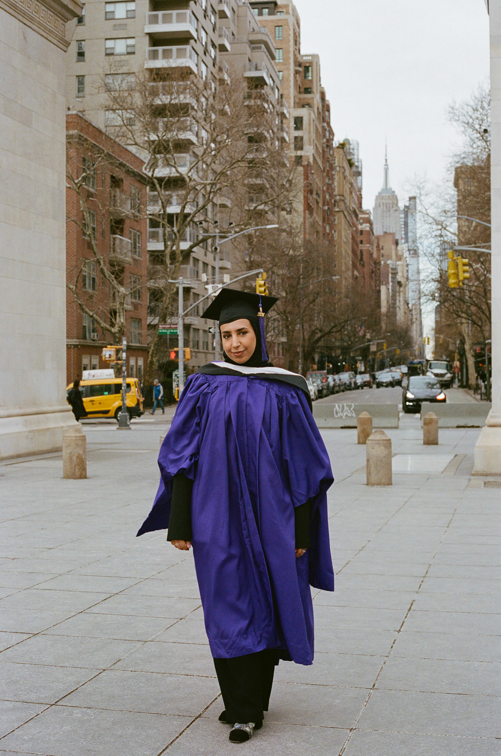 Graduate walking through Washington Square Park with city life in the background, NYC graduation photography