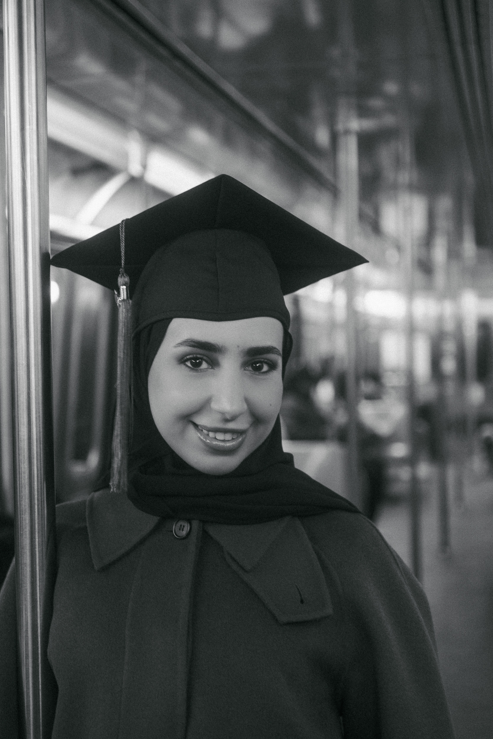 Muslim woman graduate in cap and gown standing in the NYC subway