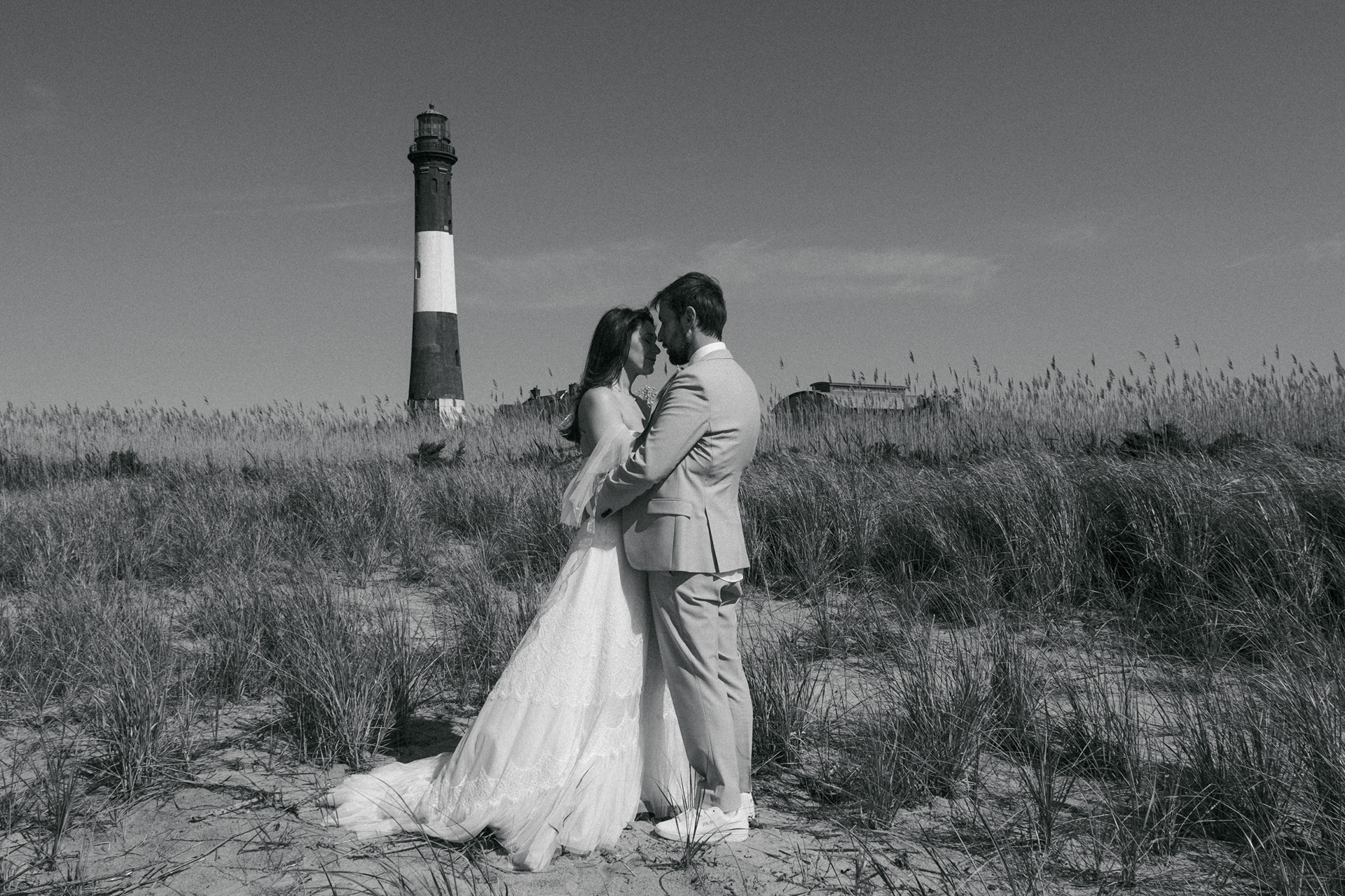 Black and white portrait of a couple during an elopement in Fire Island with the lighthouse in the background