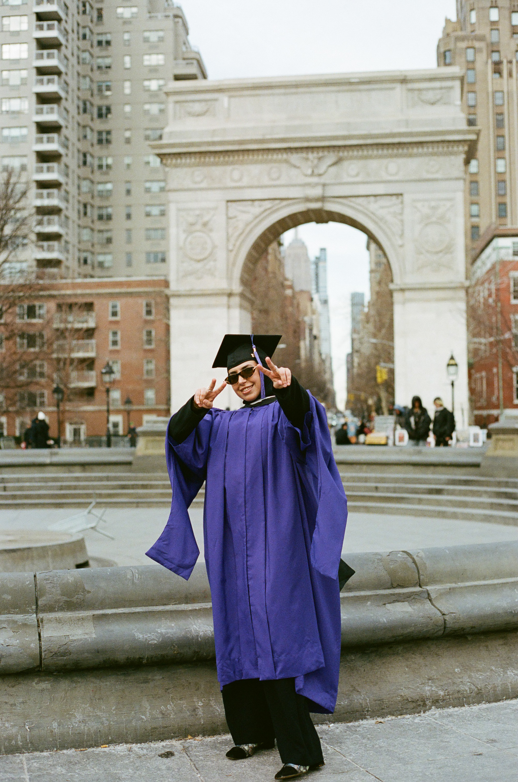 Muslim woman celebrating NYU graduation in Washington Square Park with the iconic arch in the background