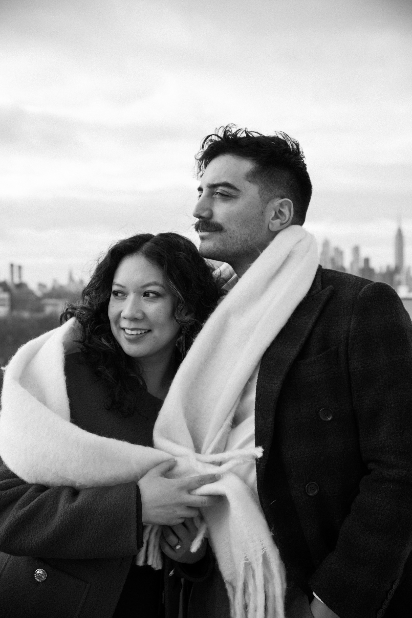Couple wrapped in a blanket during a cozy winter engagement session in Brooklyn.
