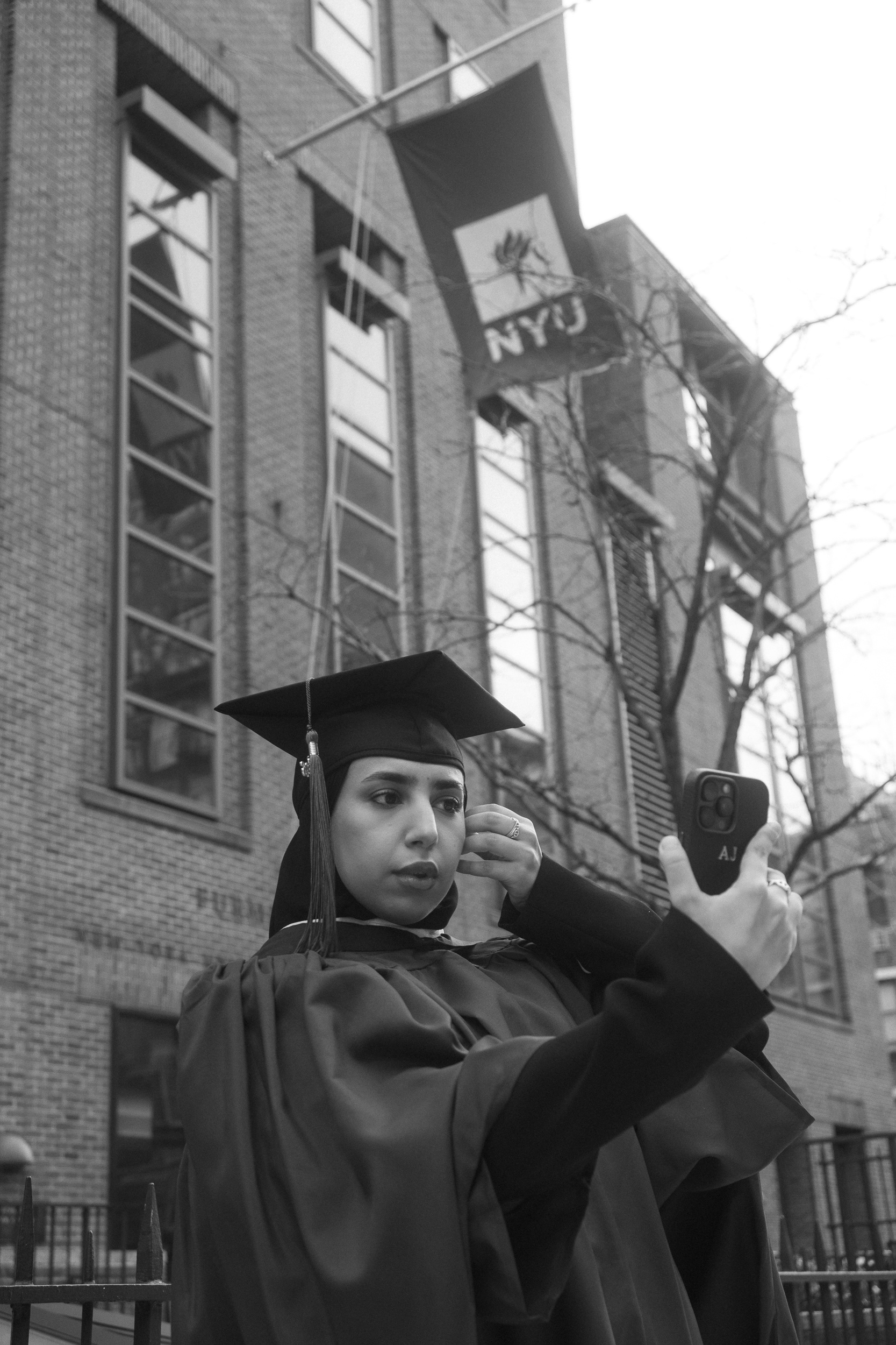 Candid moment of NYU graduate getting ready during graduation photo session in Washington Square Park