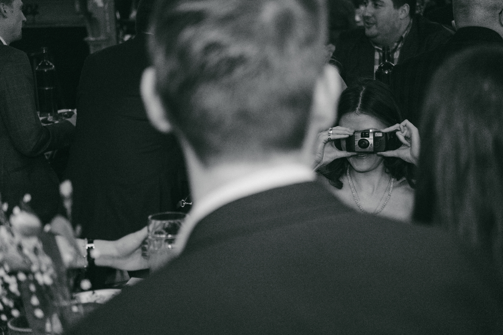 Candid photo of guests taking pictures with film cameras during a wedding party