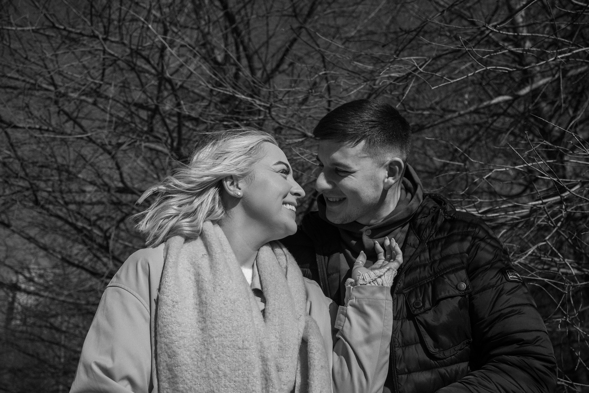 Black and white photo of a couple in front of a tree at Brooklyn Bridge Park