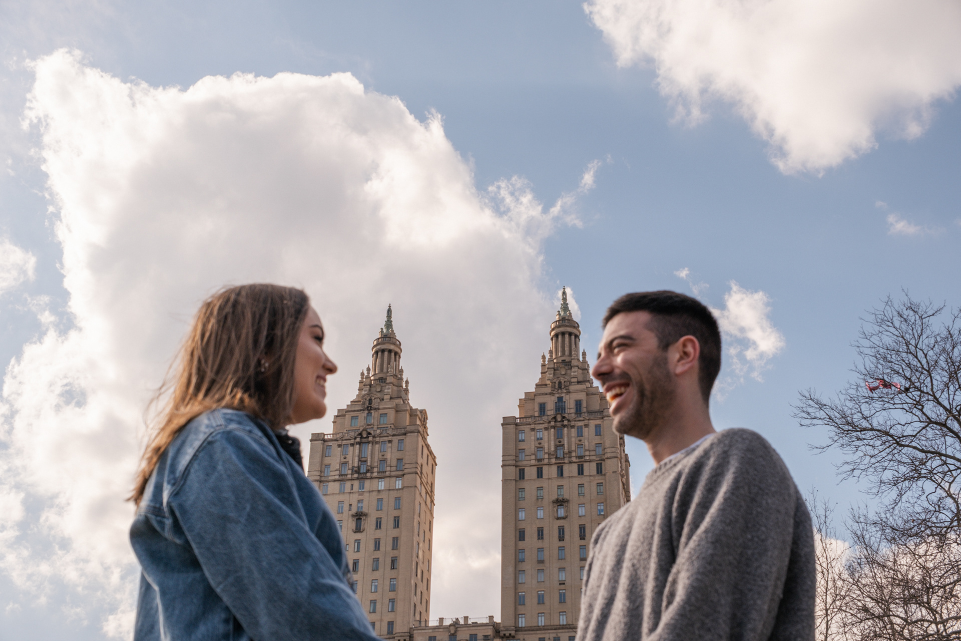 Portrait of a couple after a proposal in Central Park, with the San Remo in the background.