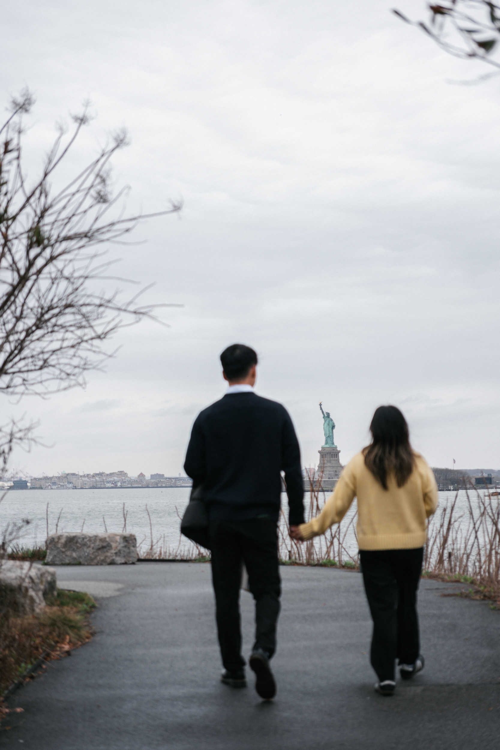 Candid photo of a couple in Governor's Island, NYC, with the Statue of Liberty in the backgroud.