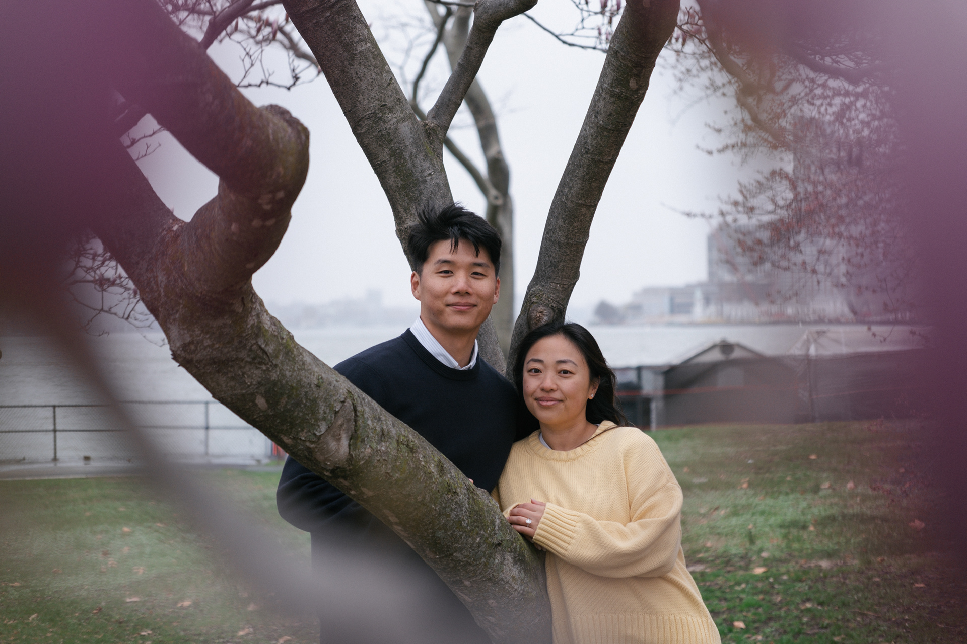 Eric & Helen framed by magnolia trees on Governors Island during engagement session