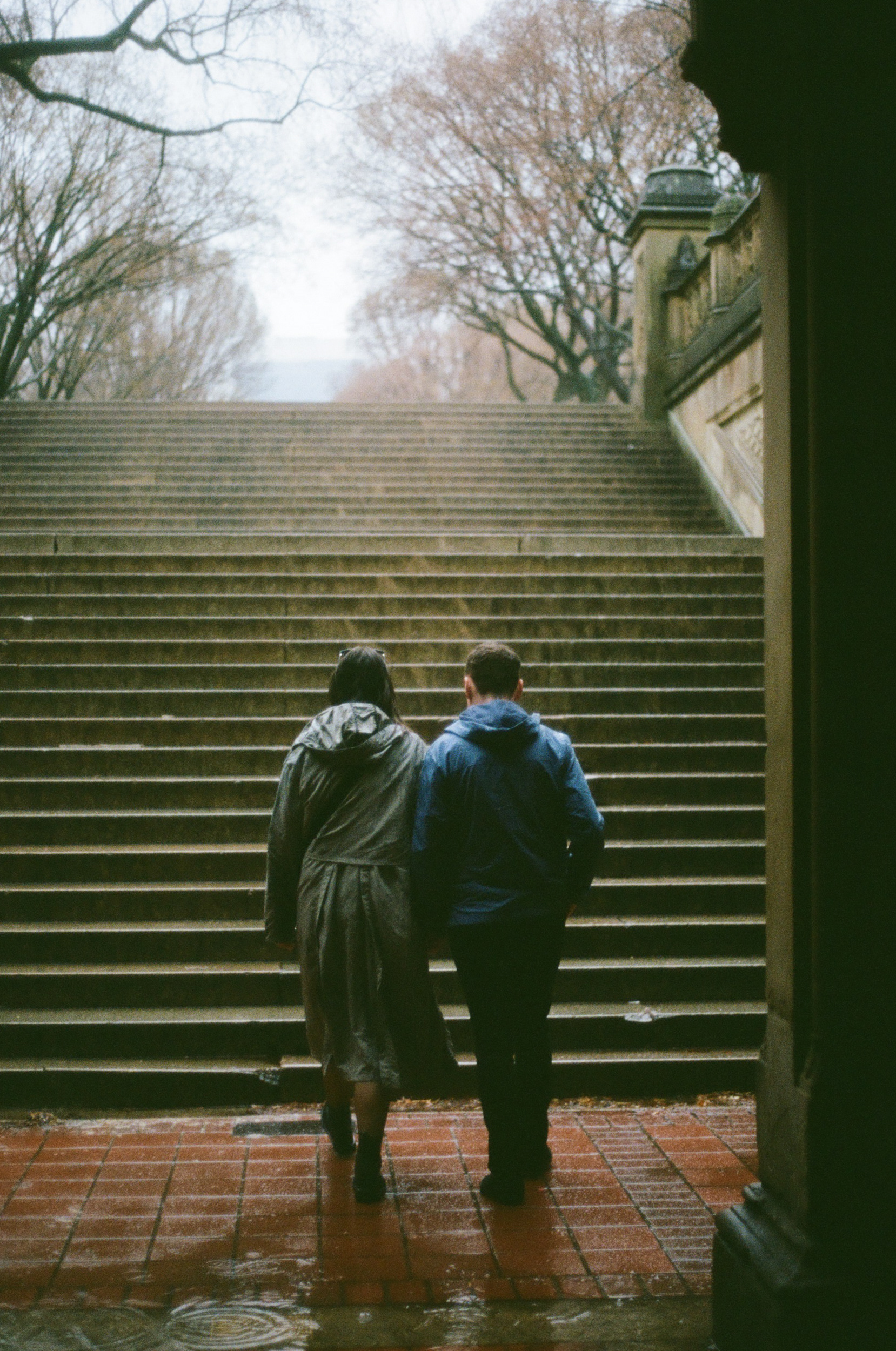 Candid moment of engaged couple walking at Bethesda Terrace, Central Park, captured on 35mm film.