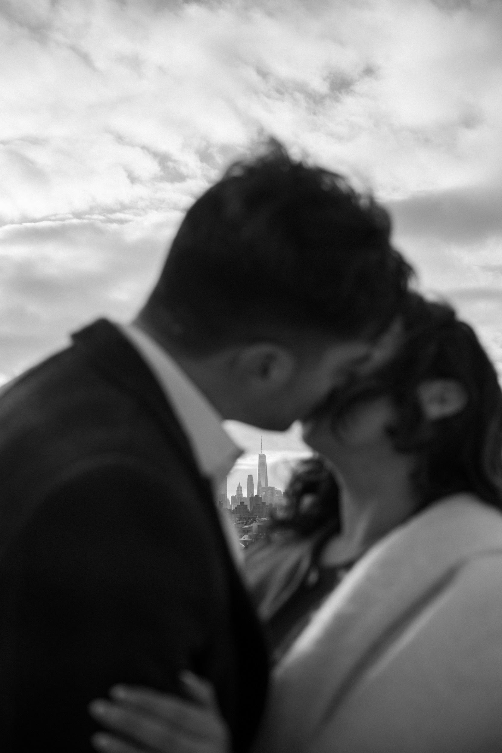 Black and white photo of a couple kissing with the One World Trade Center, Freedom Tower iin the background
