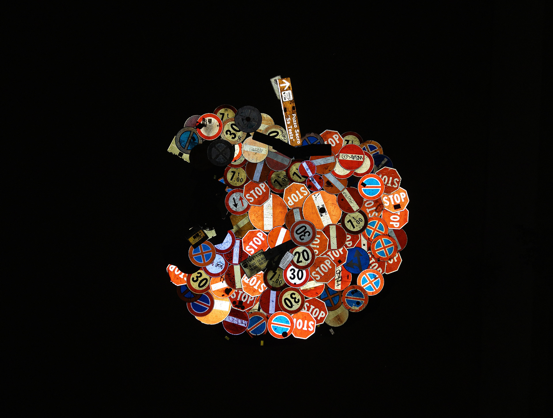 Concerto 0 illuminated at night, its retroreflective traffic signs forming a glowing apple against the dark ground.