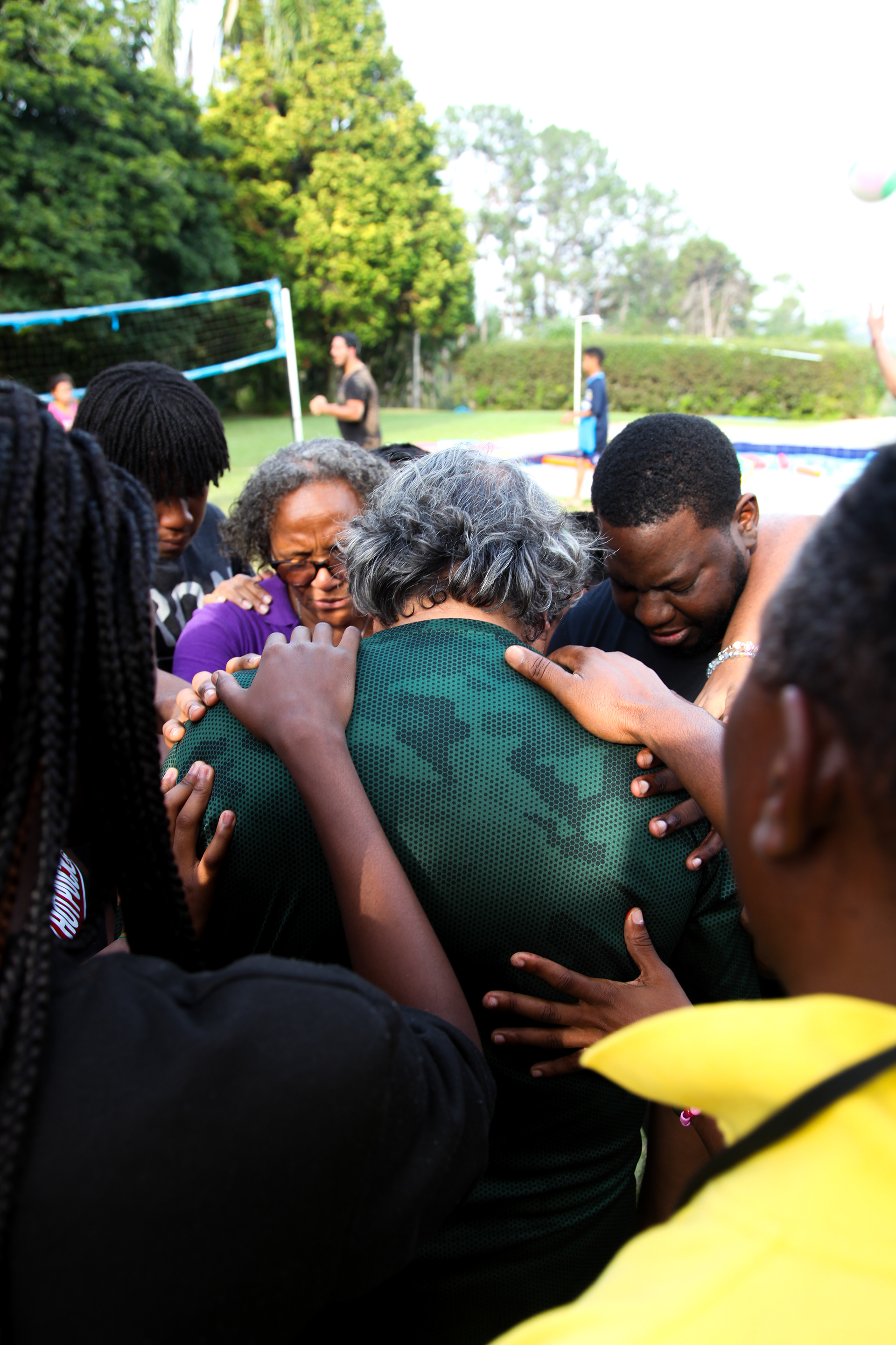 In a powerful moment of unity and faith, a circle of hands reaches out in collective support and prayer. Embraced by the warmth of the surrounding community, captured is the divine connection and shared devotion in their faith, binding them together.