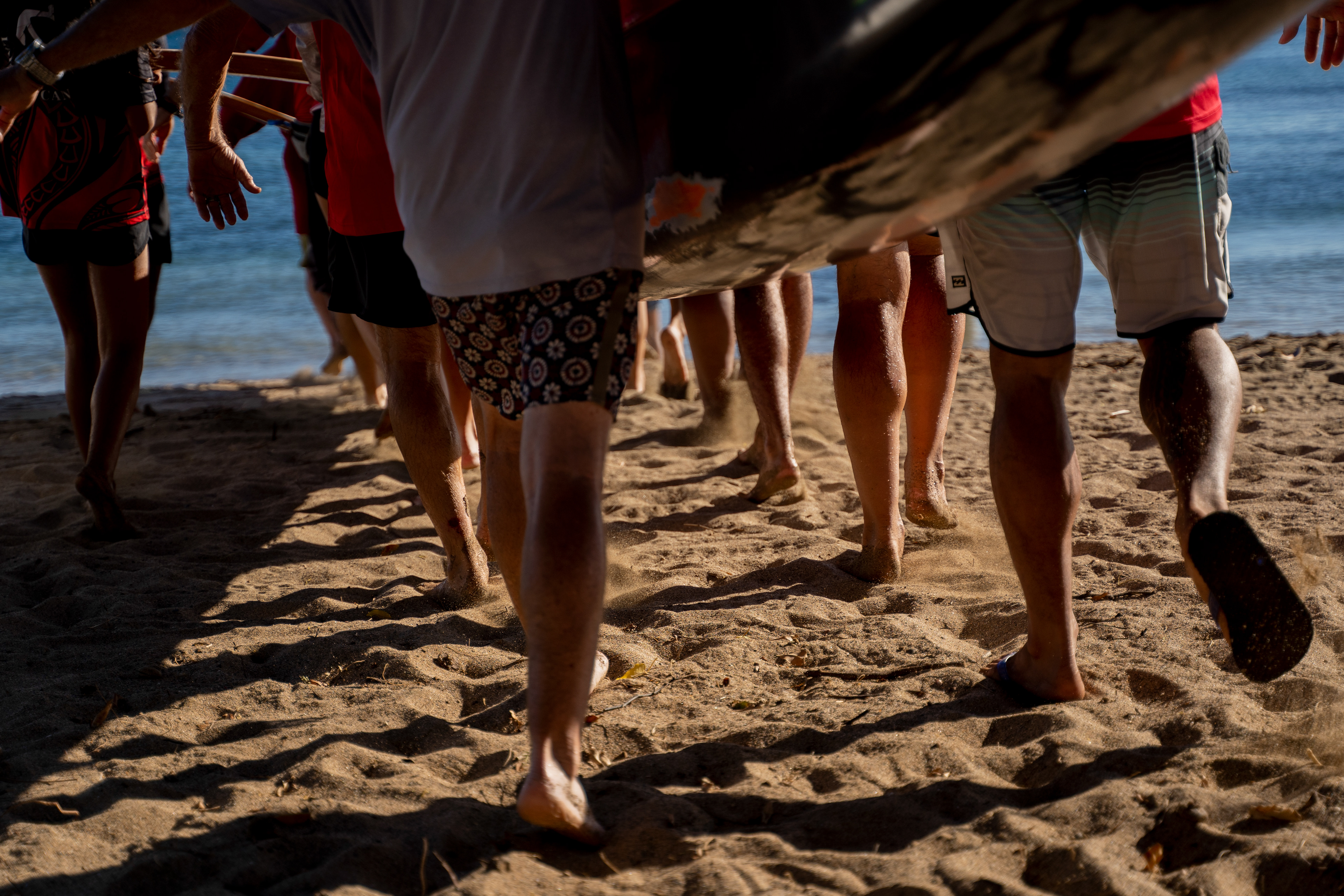 LAHAINA, HI - SEPTEMBER 8: Members of Lahaina Canoe Club carry a canoe into the water as they prepare for a memorial paddle out on the one-month anniversary of the Lahaina Fire at Hanakaoo Park in Lahaina, Hawaii on September 8, 2023. (Photo by Mengshin Lin for The Washington Post)